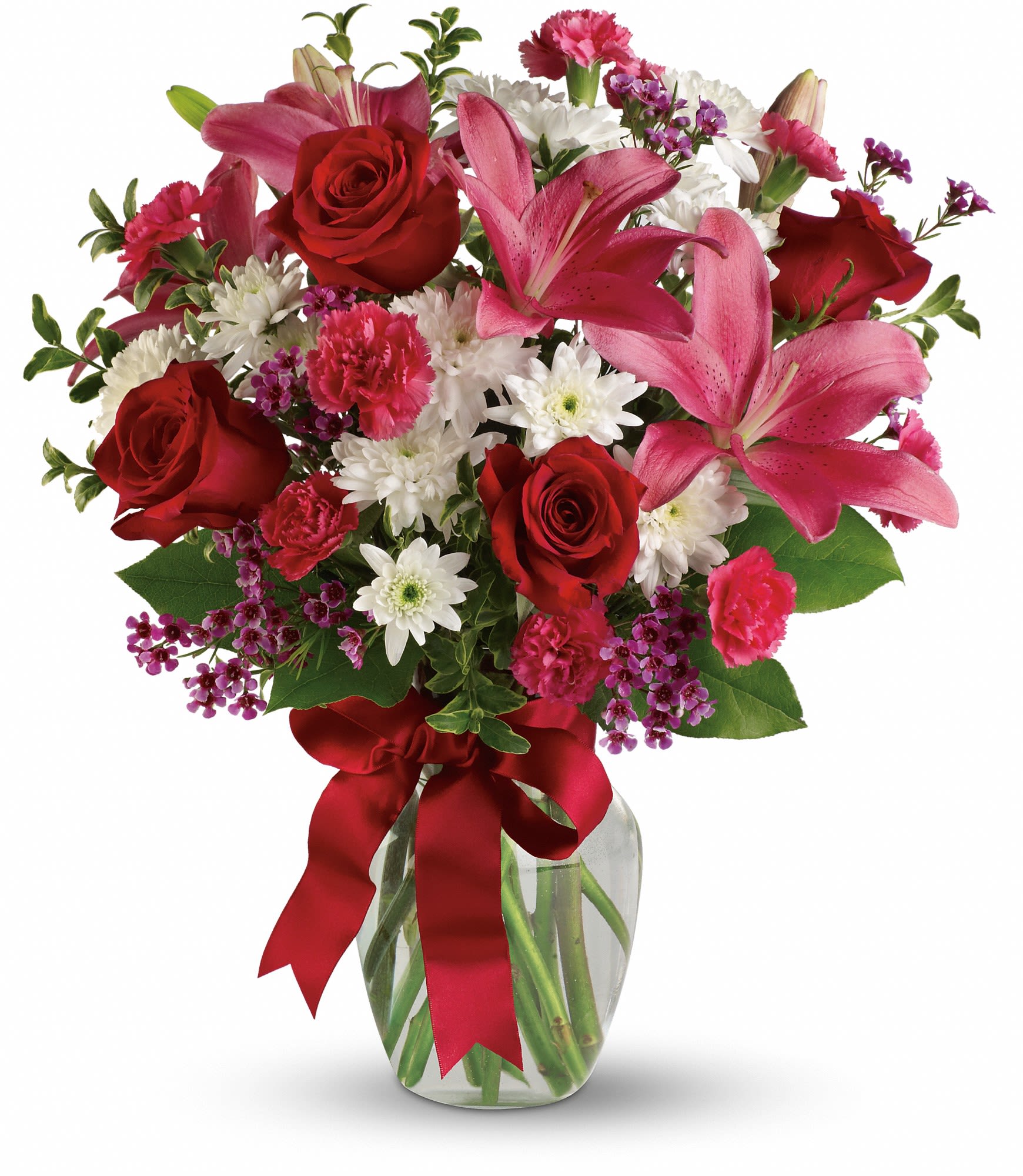 Bouquet of red roses, pink lilies, and white daisies in a glass vase with a red ribbon