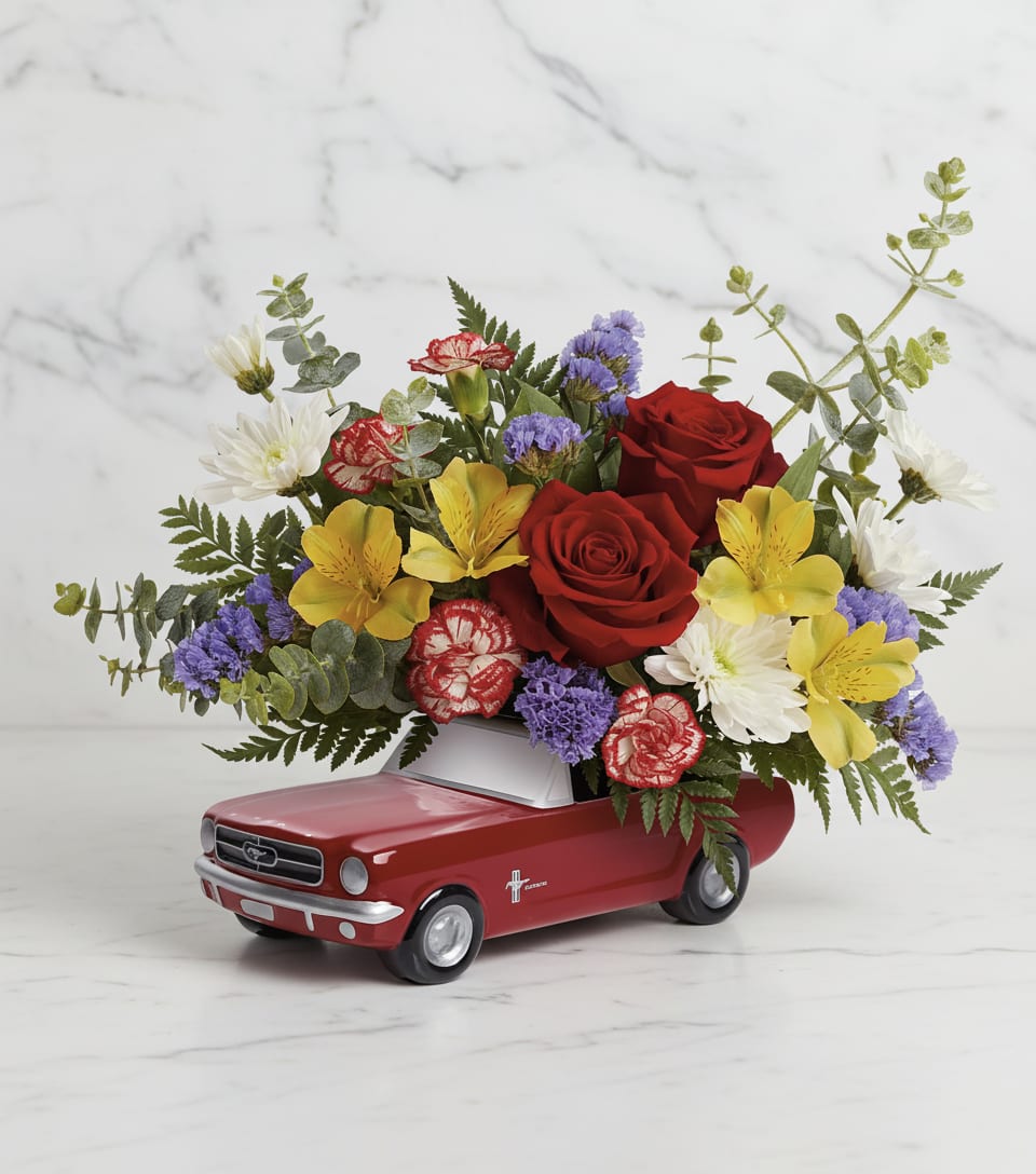 Red roses and mixed flowers arranged in a red toy car container