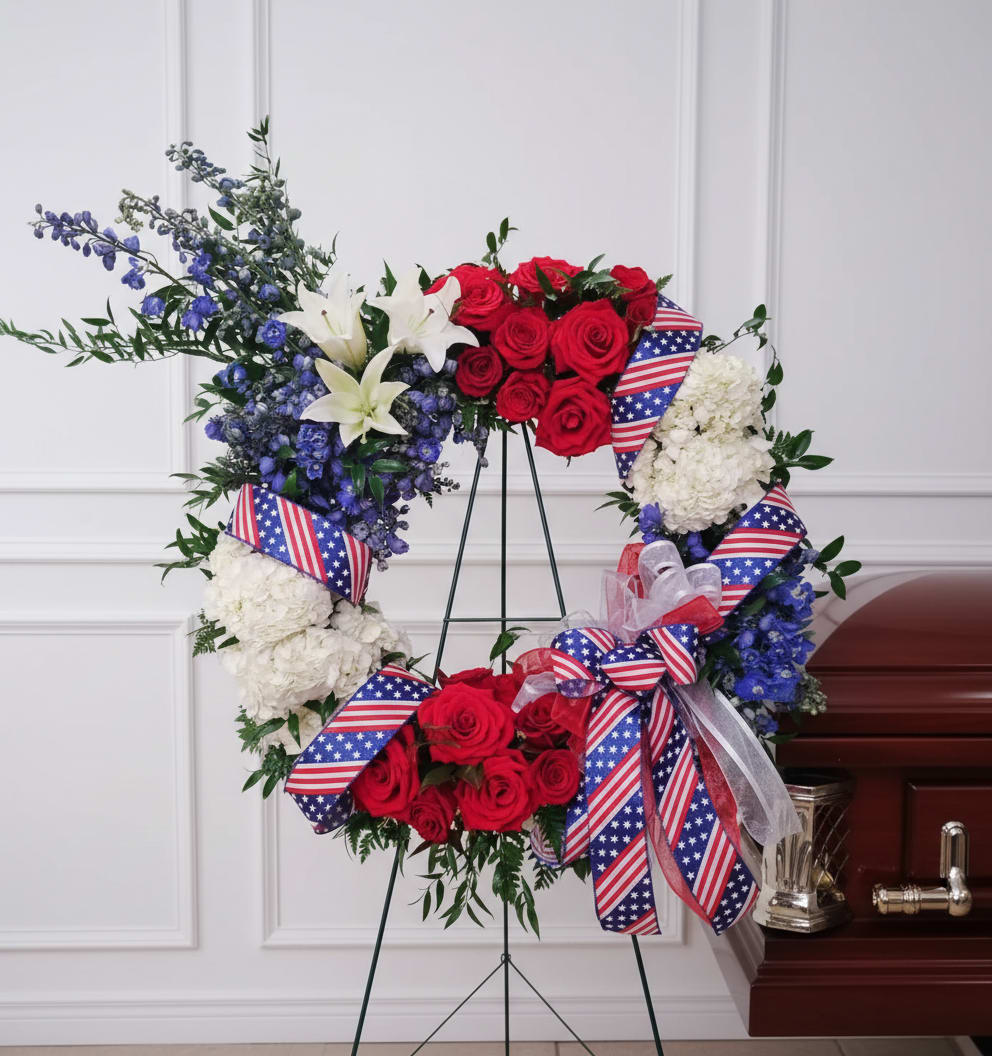 Red, white, and blue floral wreath on a stand with ribbon bows