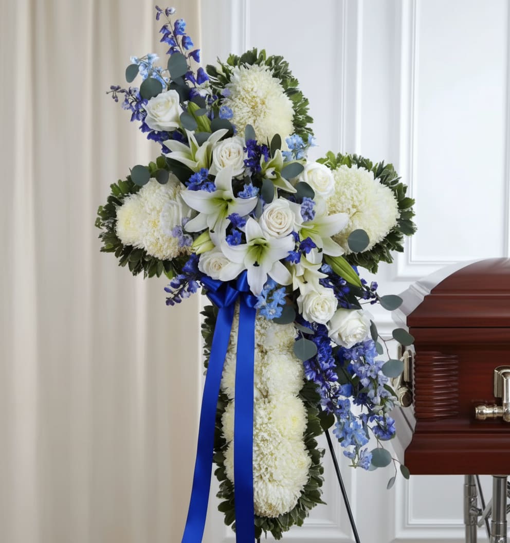 White and blue funeral spray with lilies and roses on a stand
