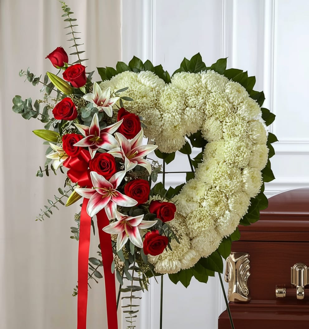 Heart-shaped floral wreath with red roses and white blooms on an easel