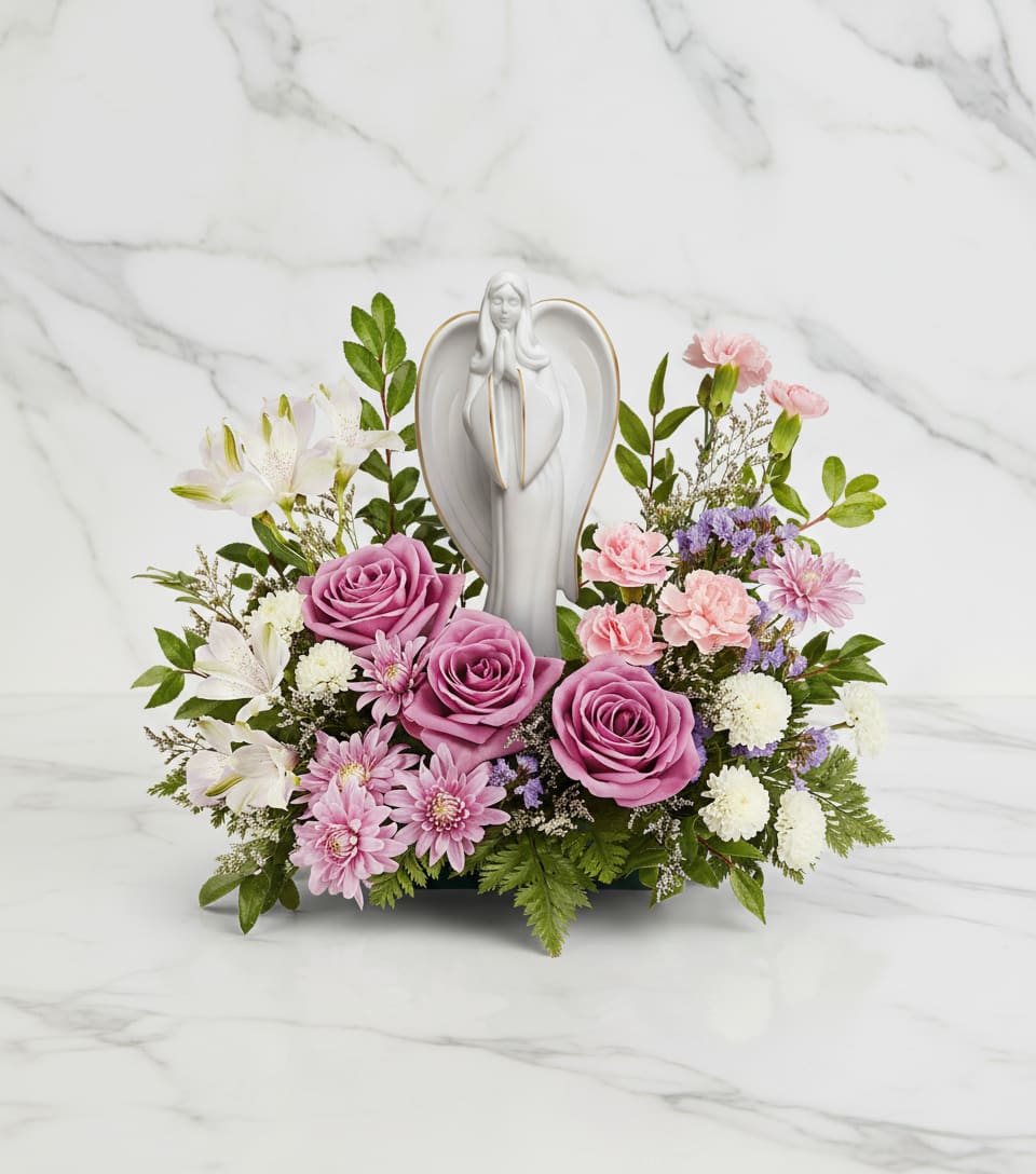 Ever So Loved Bouquet - Express gentle comfort and timeless grace with our Ever So Loved Bouquet, a serene blend of lavender roses, soft pink blooms, and delicate white flowers surrounding a porcelain angel keepsake.