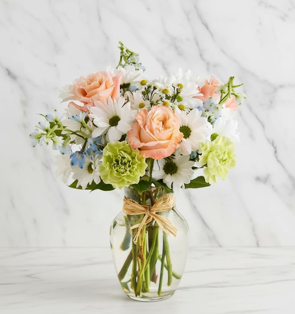 Summer Dunes - Our beach-inspired bouquet captures the blissful beauty of a seaside retreat. Bunches of blooms in cool, soothing shades are arranged in a glass vase tied with raffia for an extra touch of coastal style. It’s a gift that celebrates the carefree spirit of 
