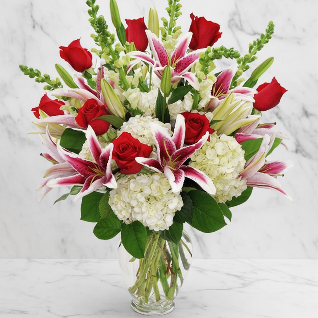 Bouquet of red roses, pink lilies, and white hydrangeas in a clear glass vase