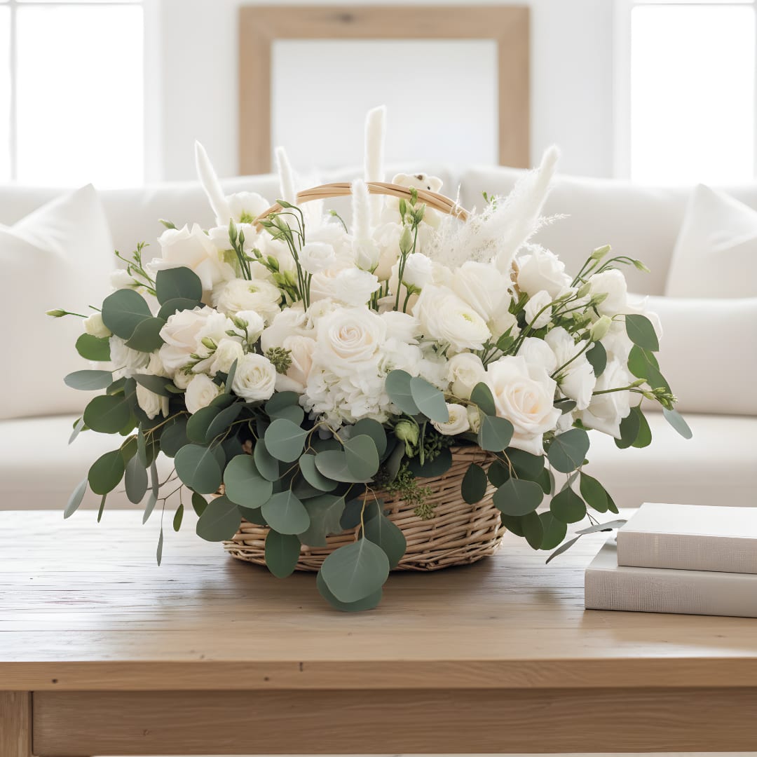 White floral arrangement in a wicker basket with eucalyptus