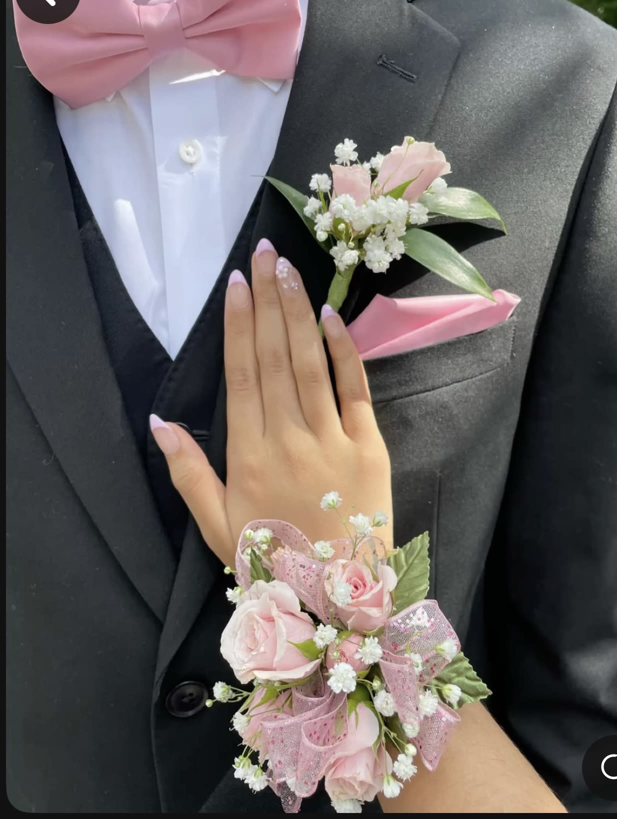 Pink rose boutonniere and wrist corsage on a black suit