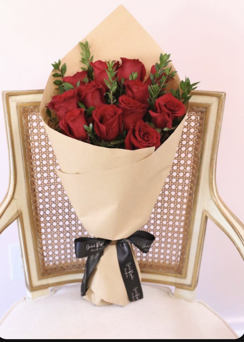 Bouquet of red roses wrapped in tan paper with a black ribbon