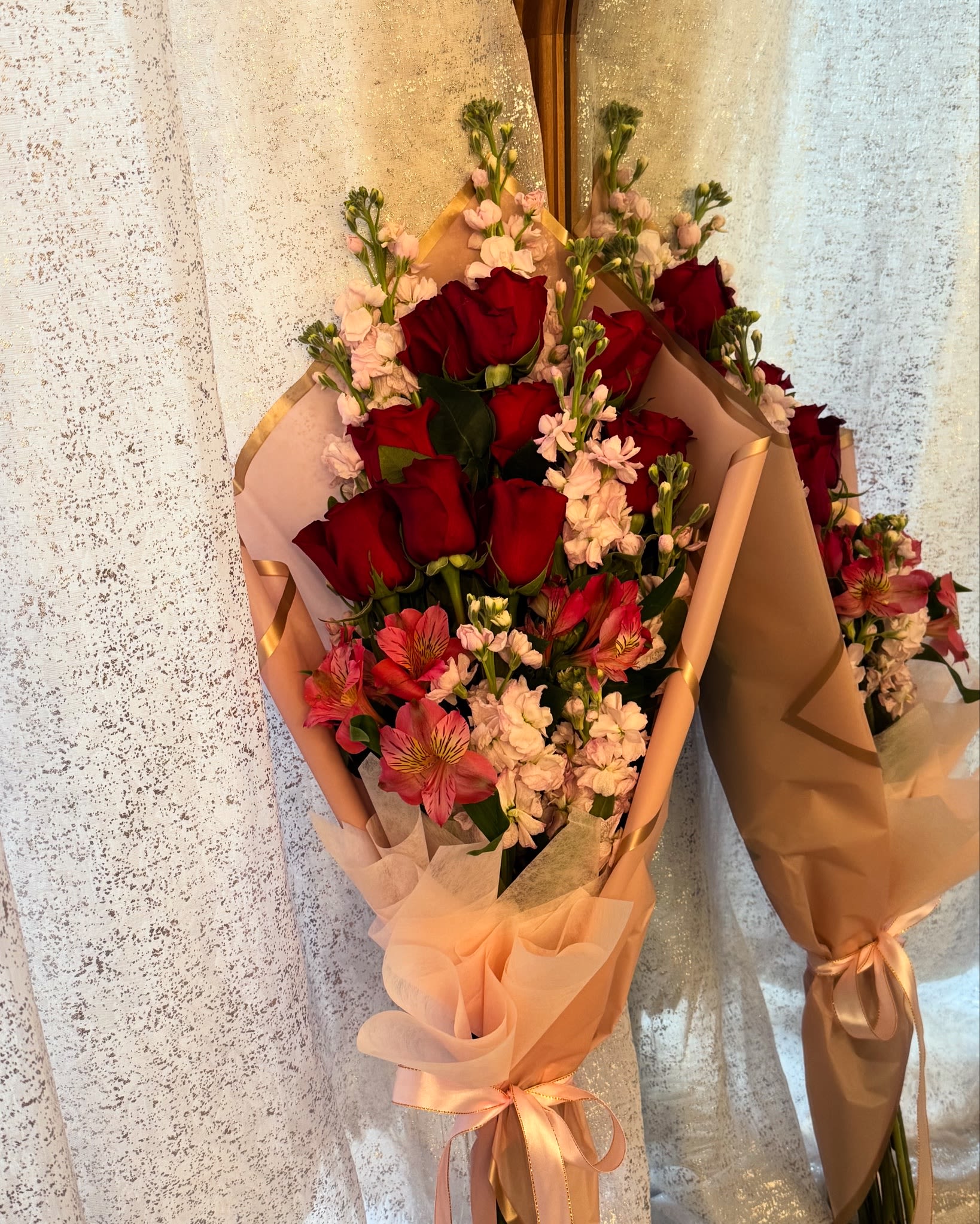 Bouquets of red roses and pink flowers wrapped in peach paper