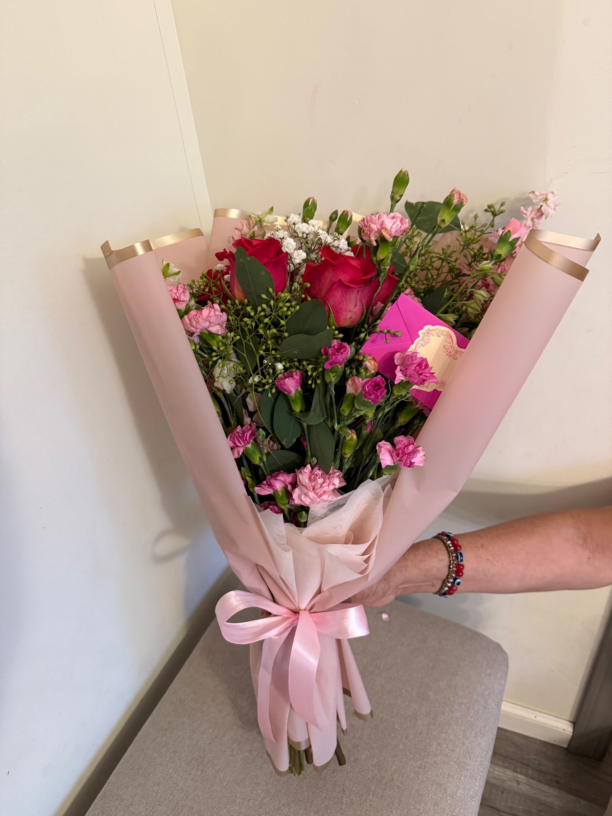 Pink bouquet with red roses and carnations wrapped in blush paper