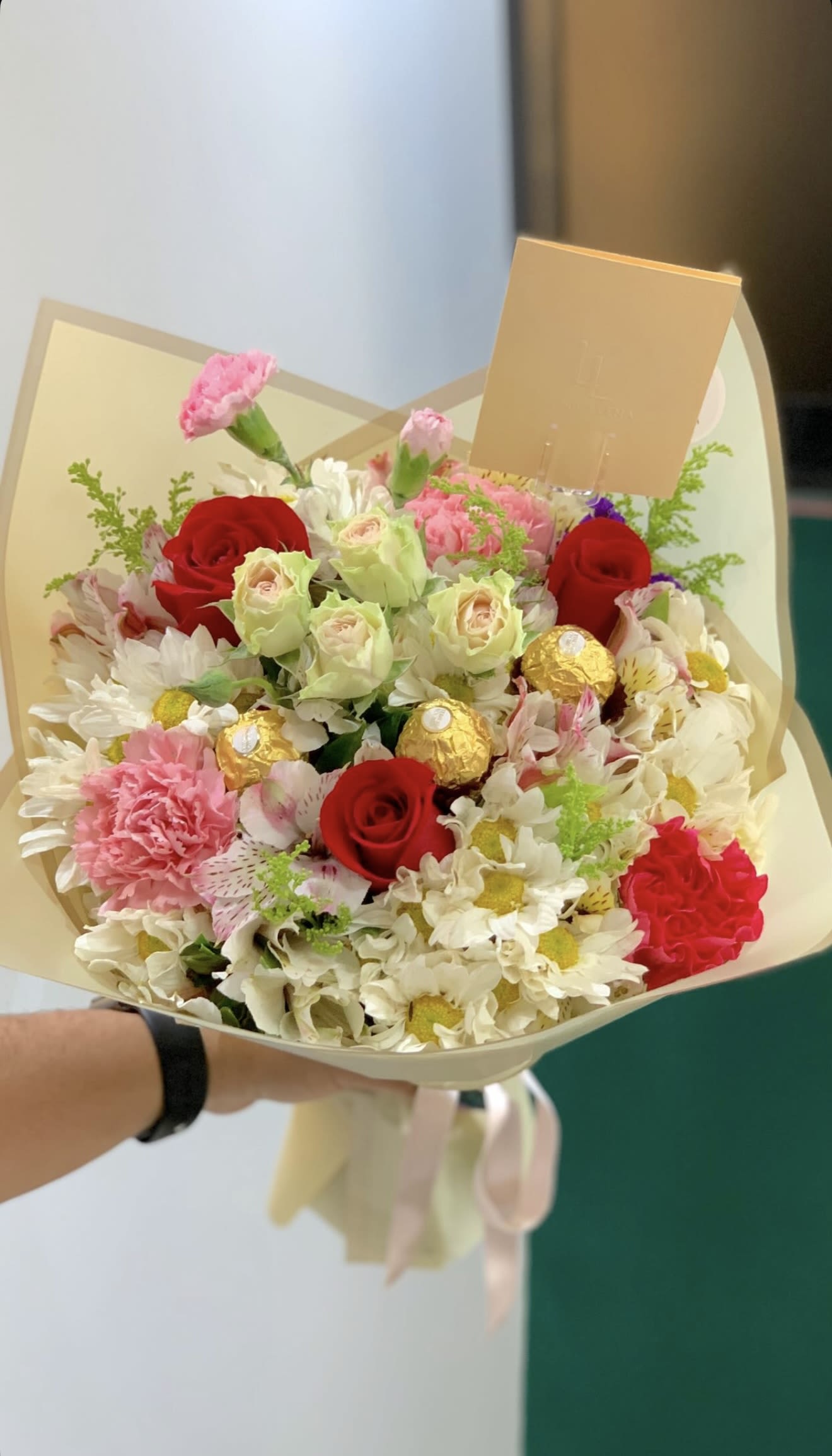 Bouquet of red roses, pink carnations, and white daisies with gold chocolates