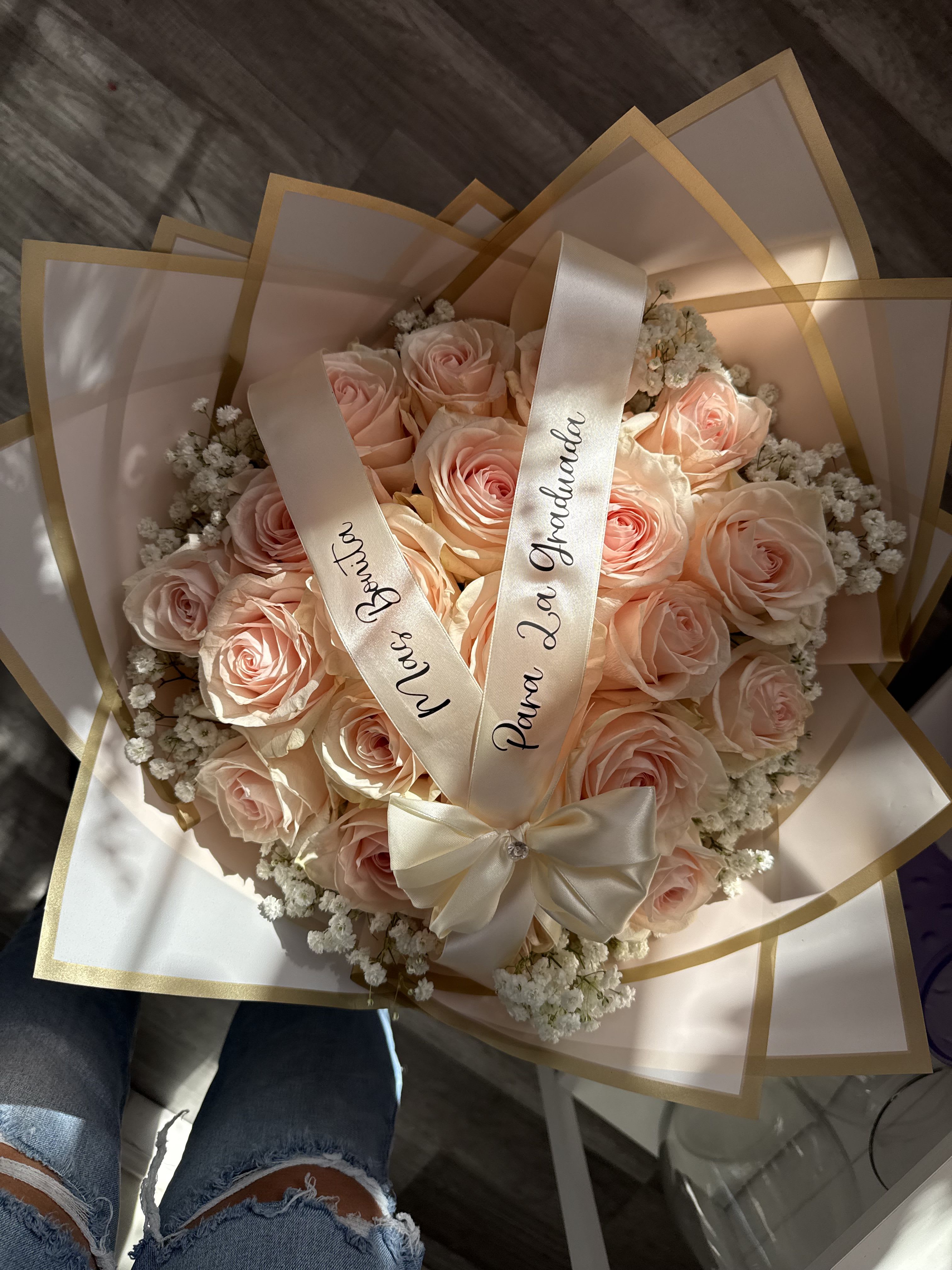 Bouquet of pale pink roses wrapped in cream paper with satin ribbons