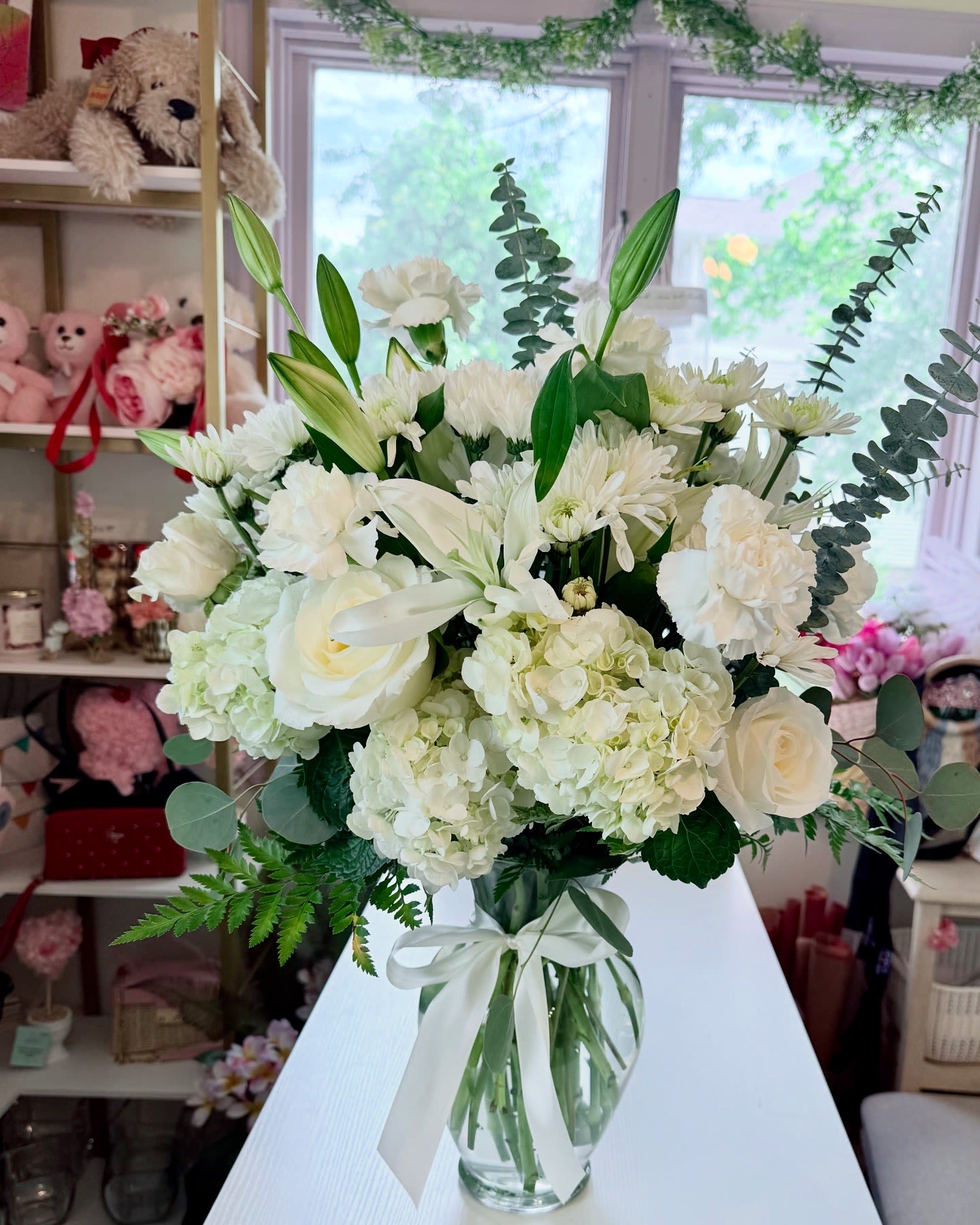 White floral bouquet in a clear glass vase with a ribbon