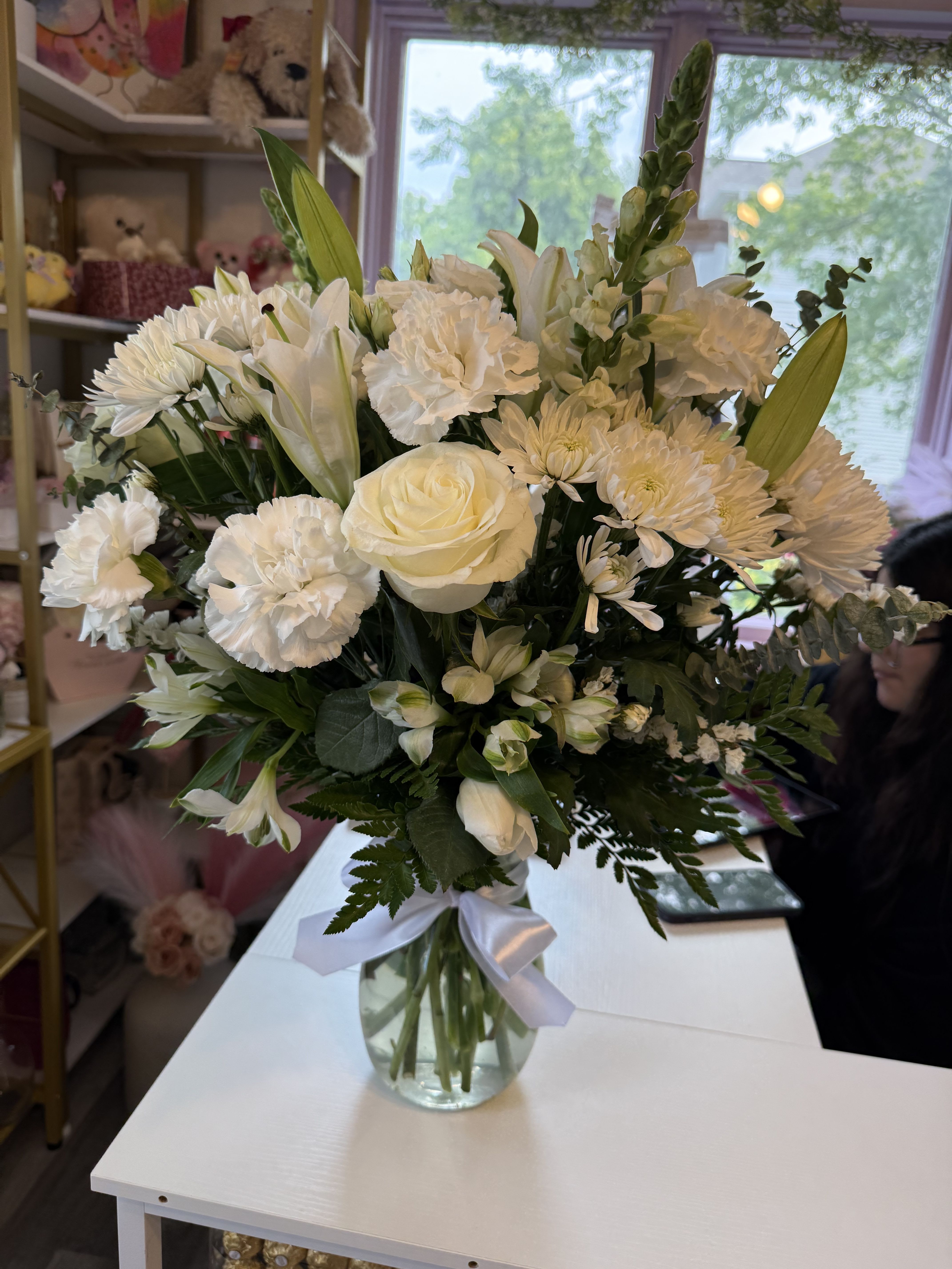 White floral bouquet in a glass vase with a white ribbon