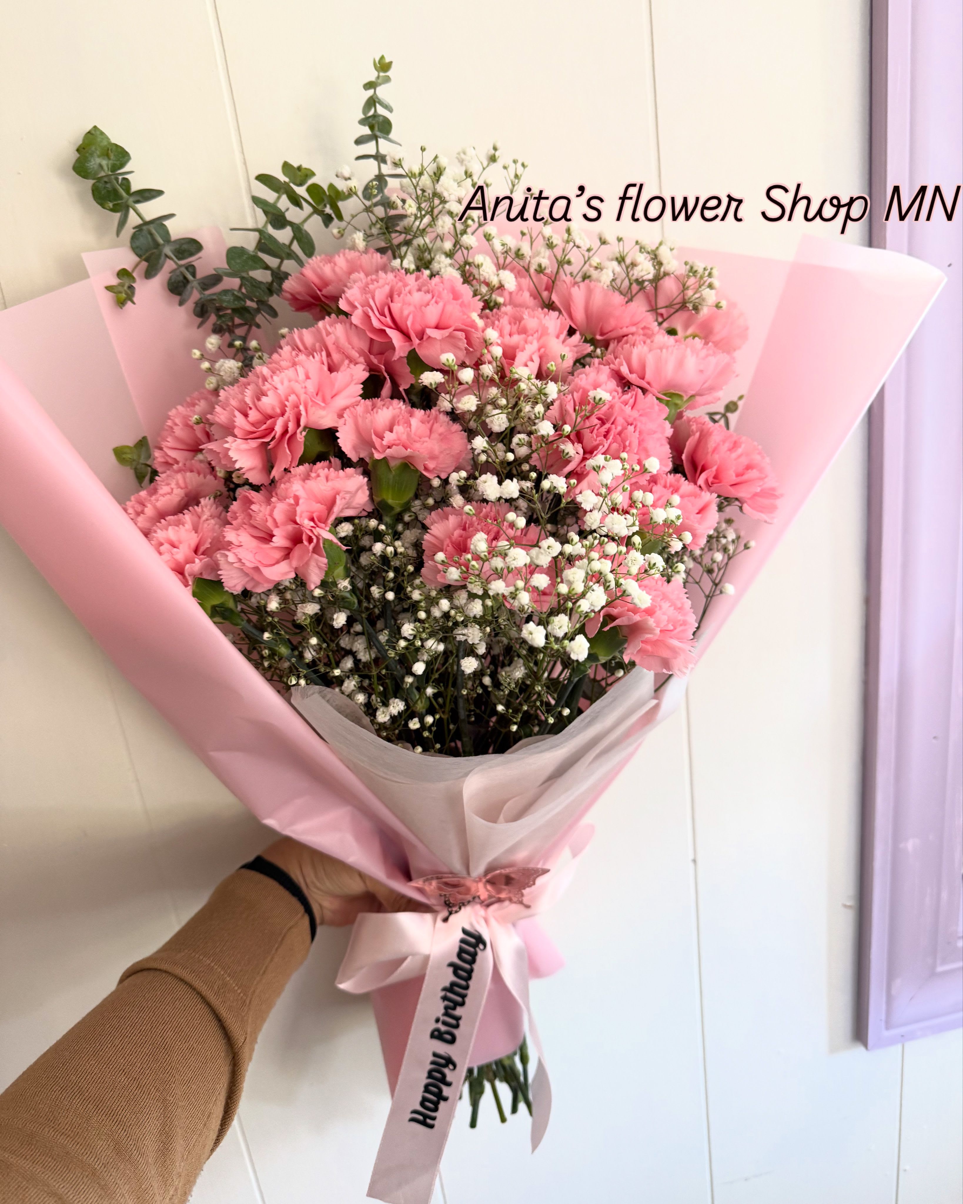 Pink carnation bouquet wrapped in pastel paper with a birthday ribbon