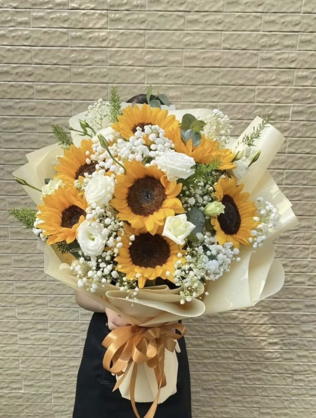 Bouquet of sunflowers and white blooms wrapped in cream paper
