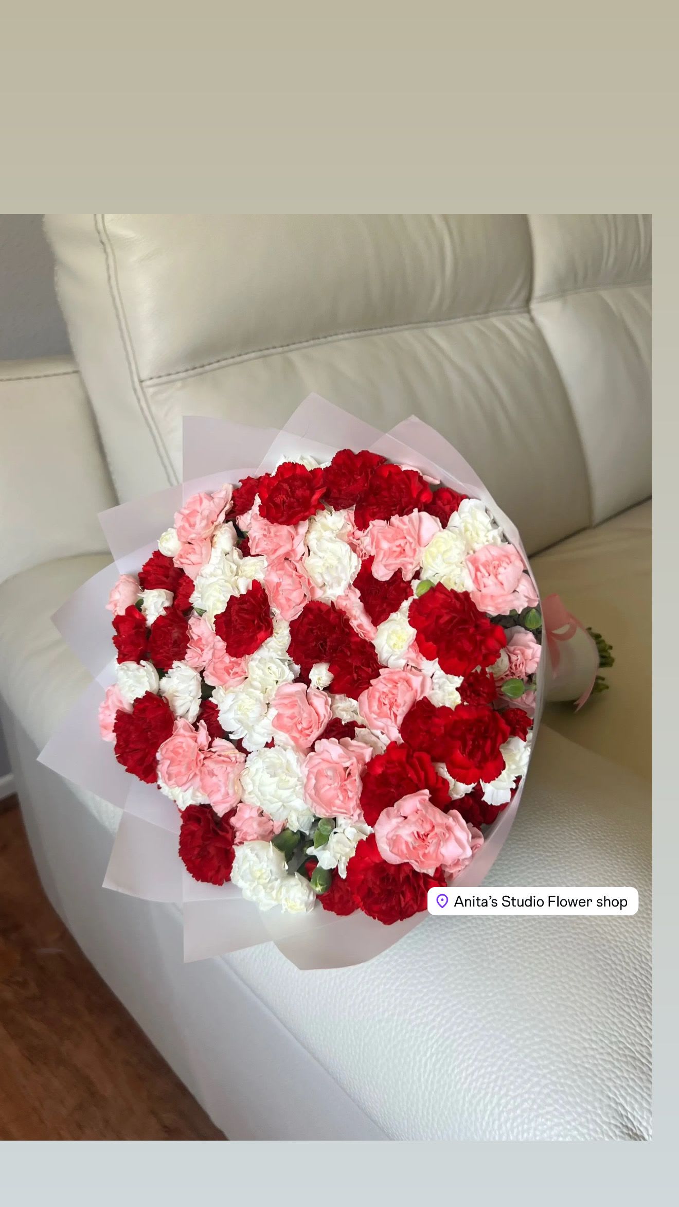 Bouquet of red, pink, and white carnations wrapped in pale paper