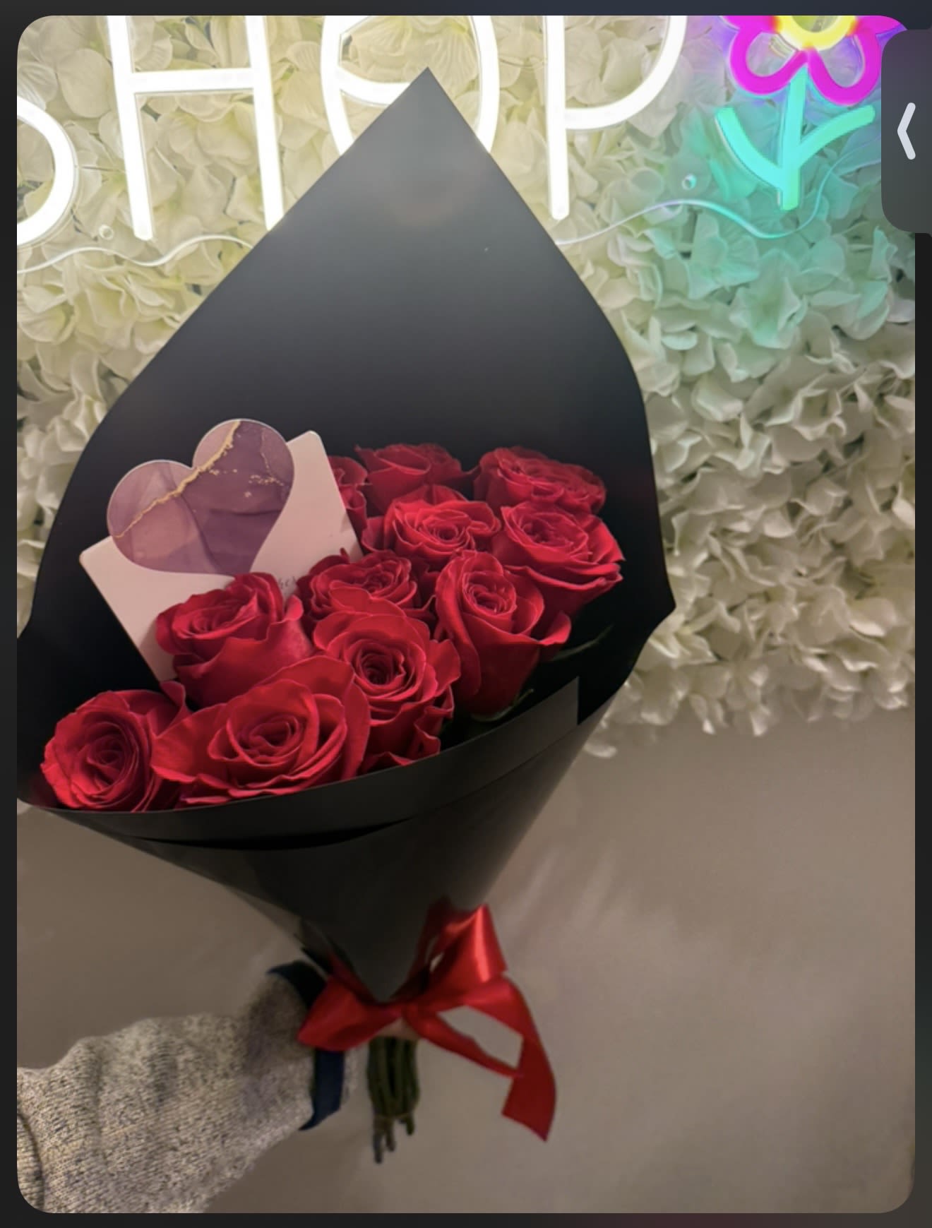 Bouquet of red roses wrapped in black paper with a red ribbon