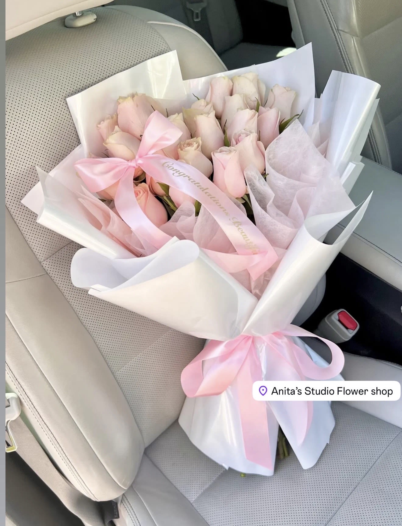 Bouquet of pale pink roses wrapped in white and pink paper with a ribbon
