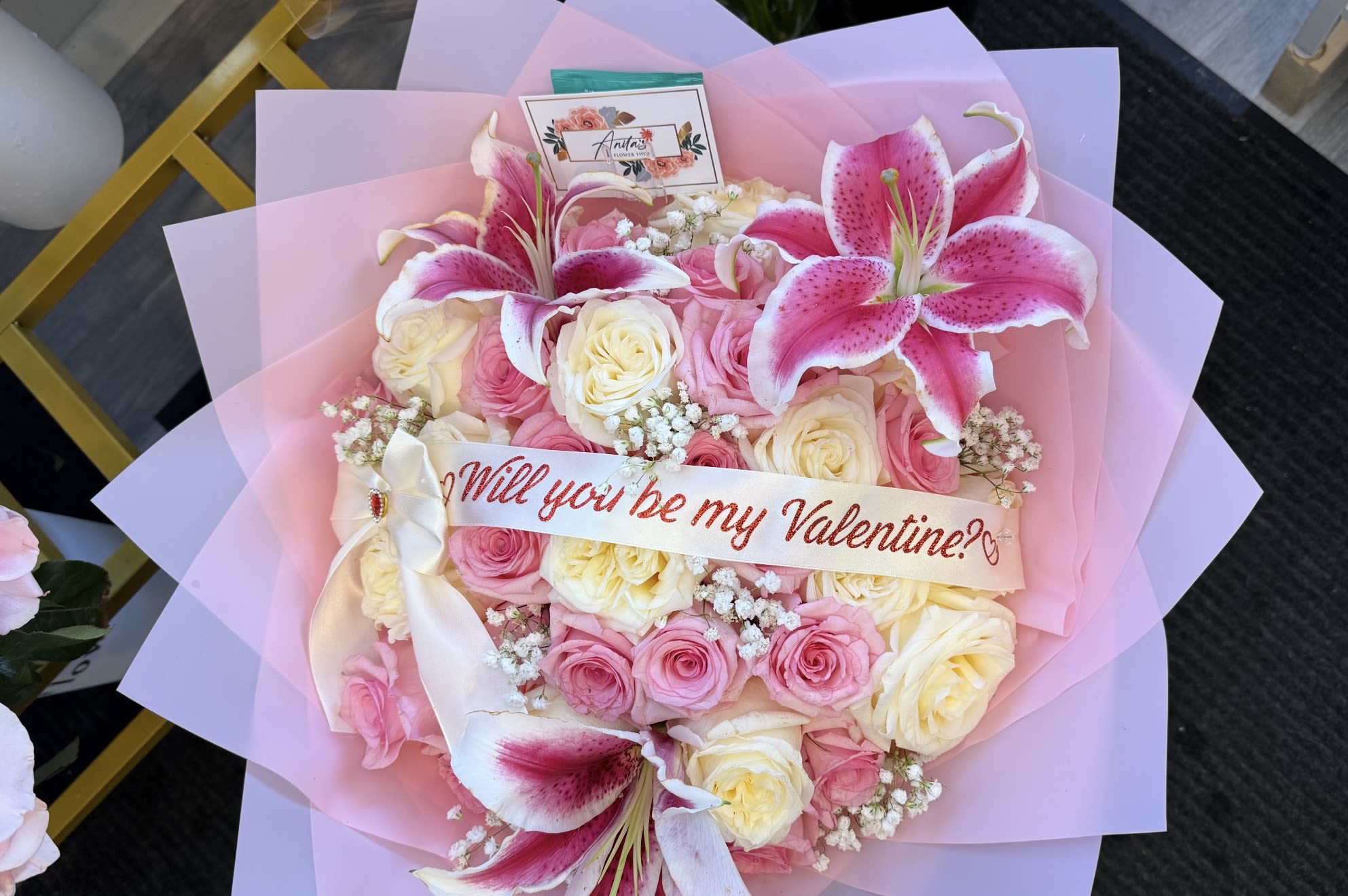 Heart-shaped bouquet of pink and cream roses with lilies and a Valentine ribbon