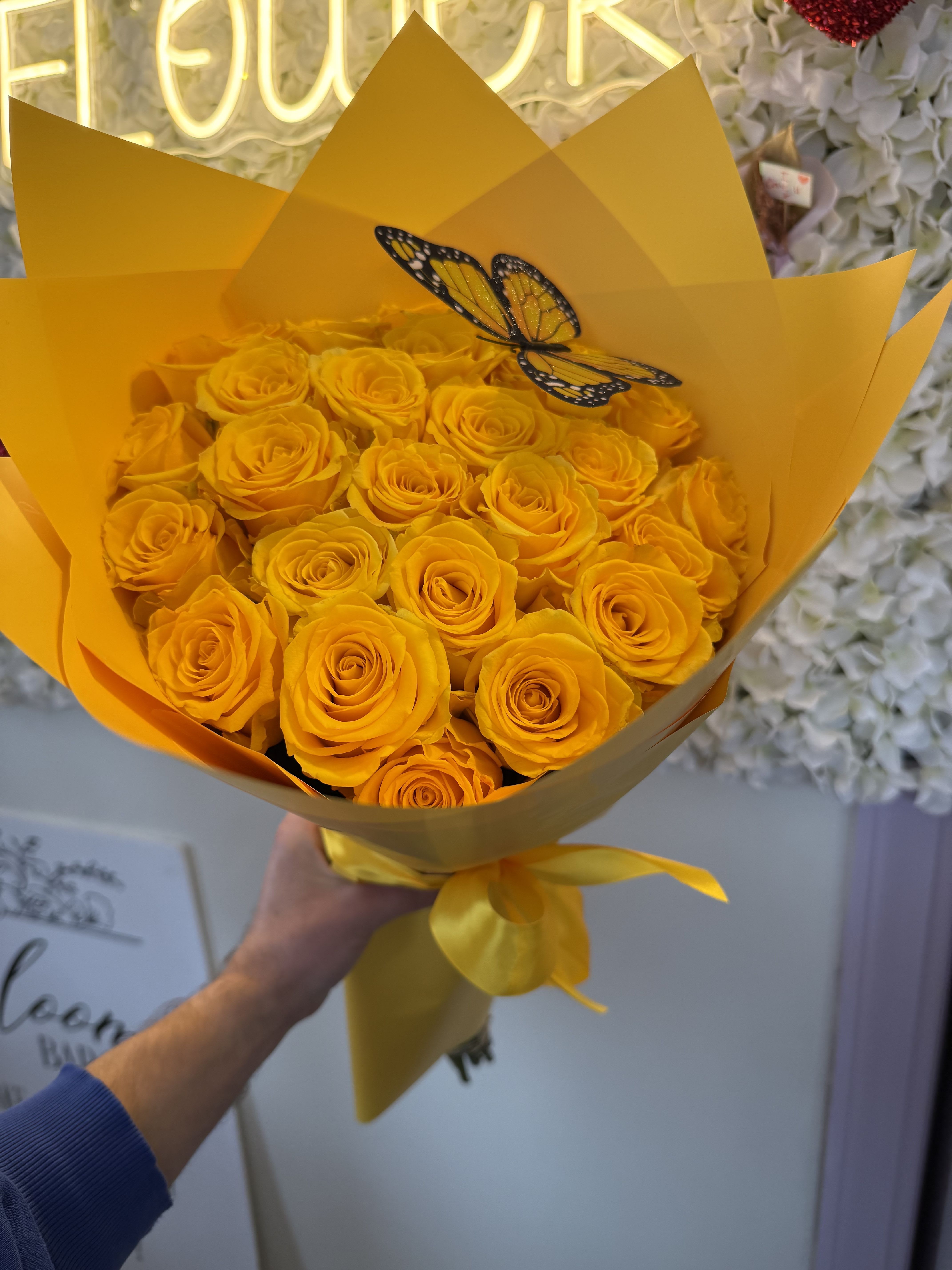Bouquet of yellow roses wrapped in bright yellow paper with a butterfly decoration