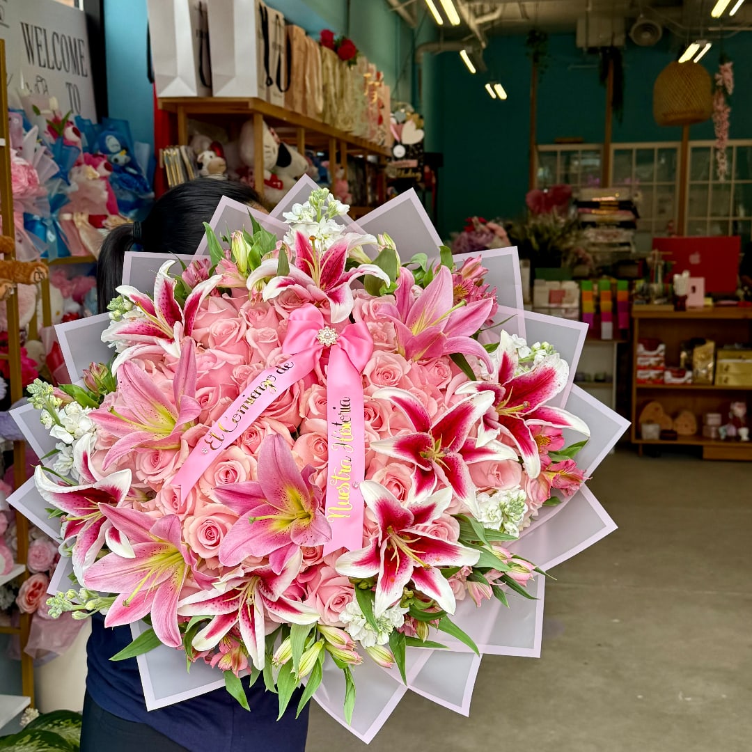 Large pink bouquet with roses and lilies, wrapped in pale paper with ribbons