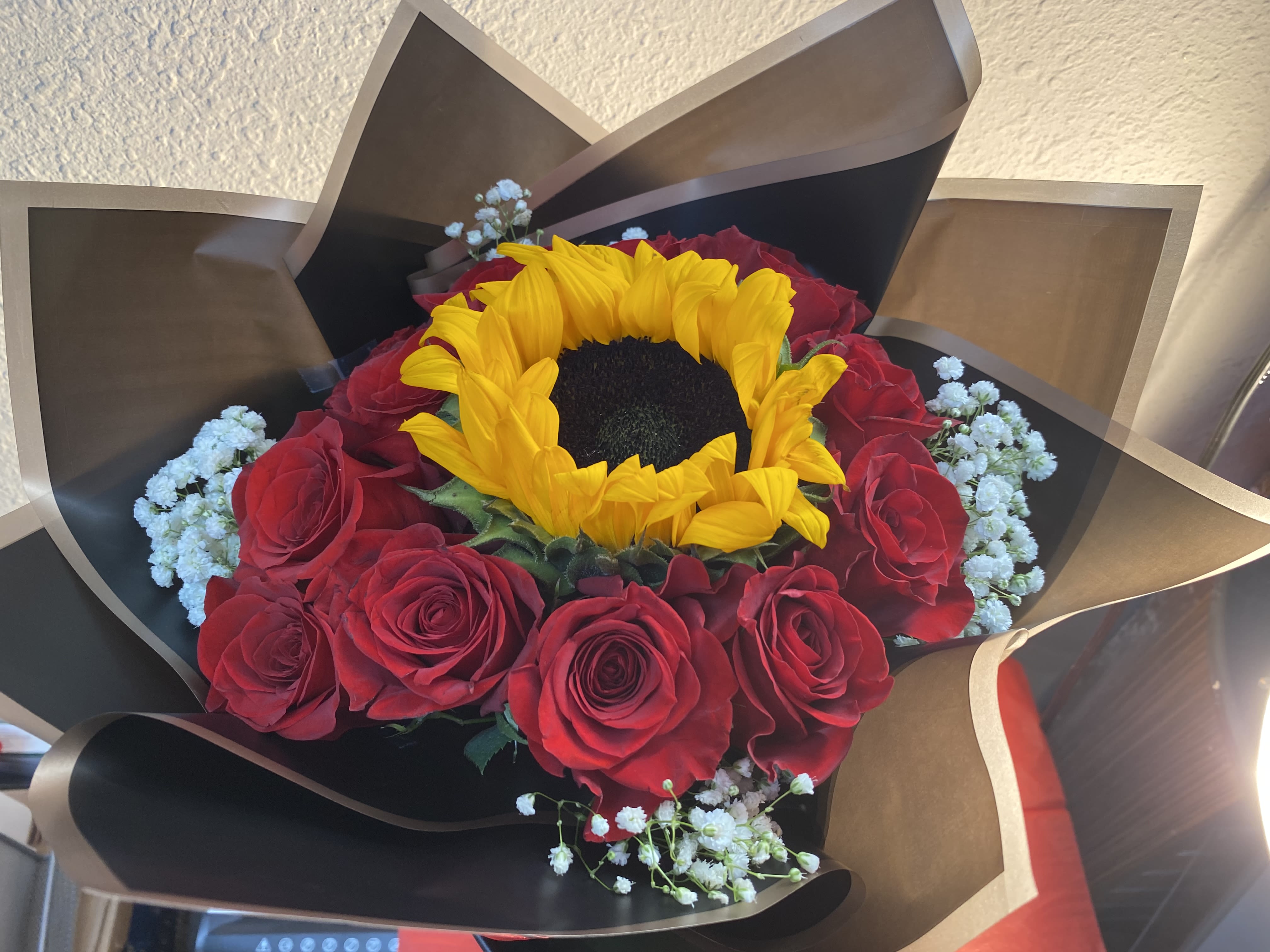 Bouquet of red roses with a yellow sunflower and white baby's breath