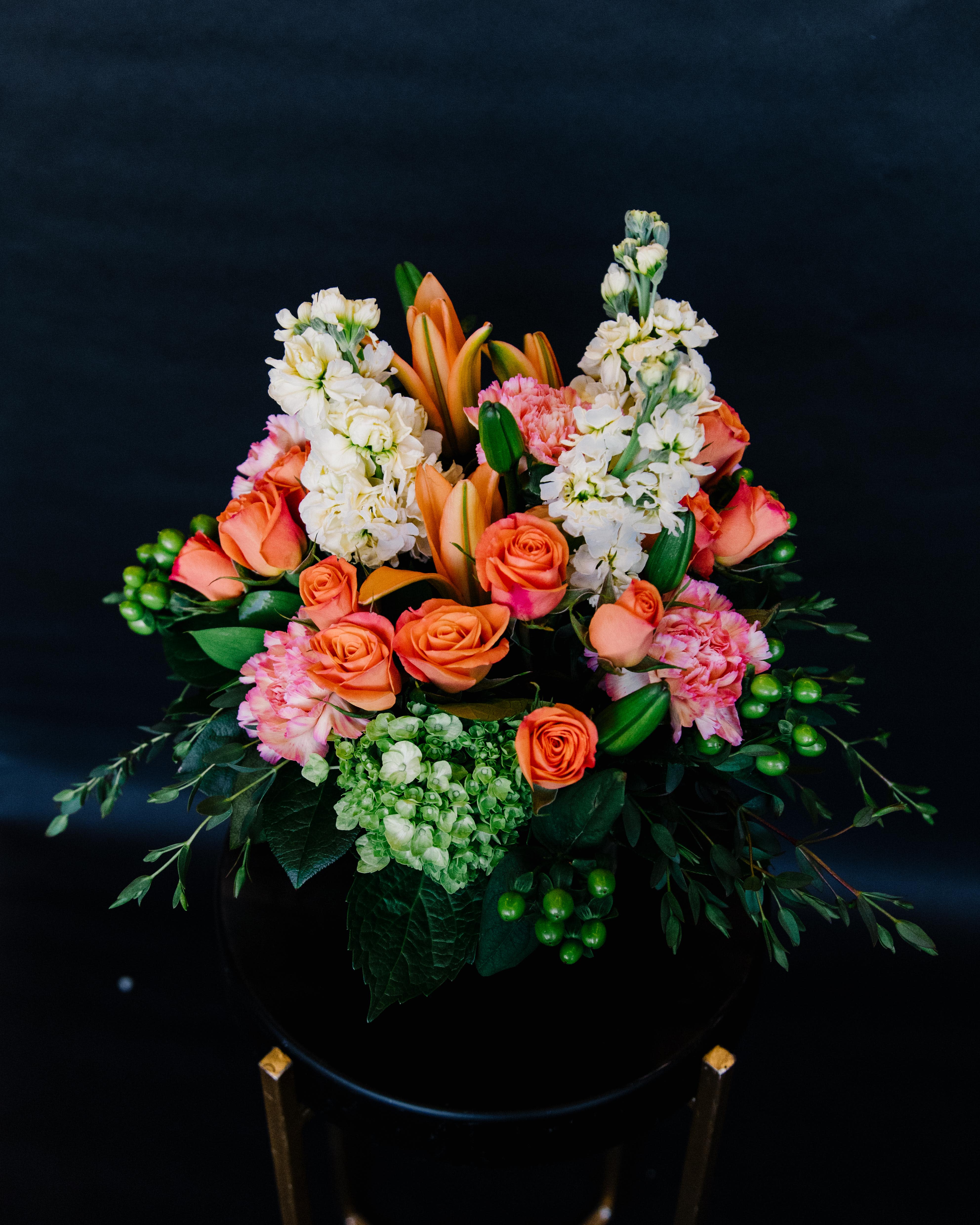 Orange roses and white stock in a black vase