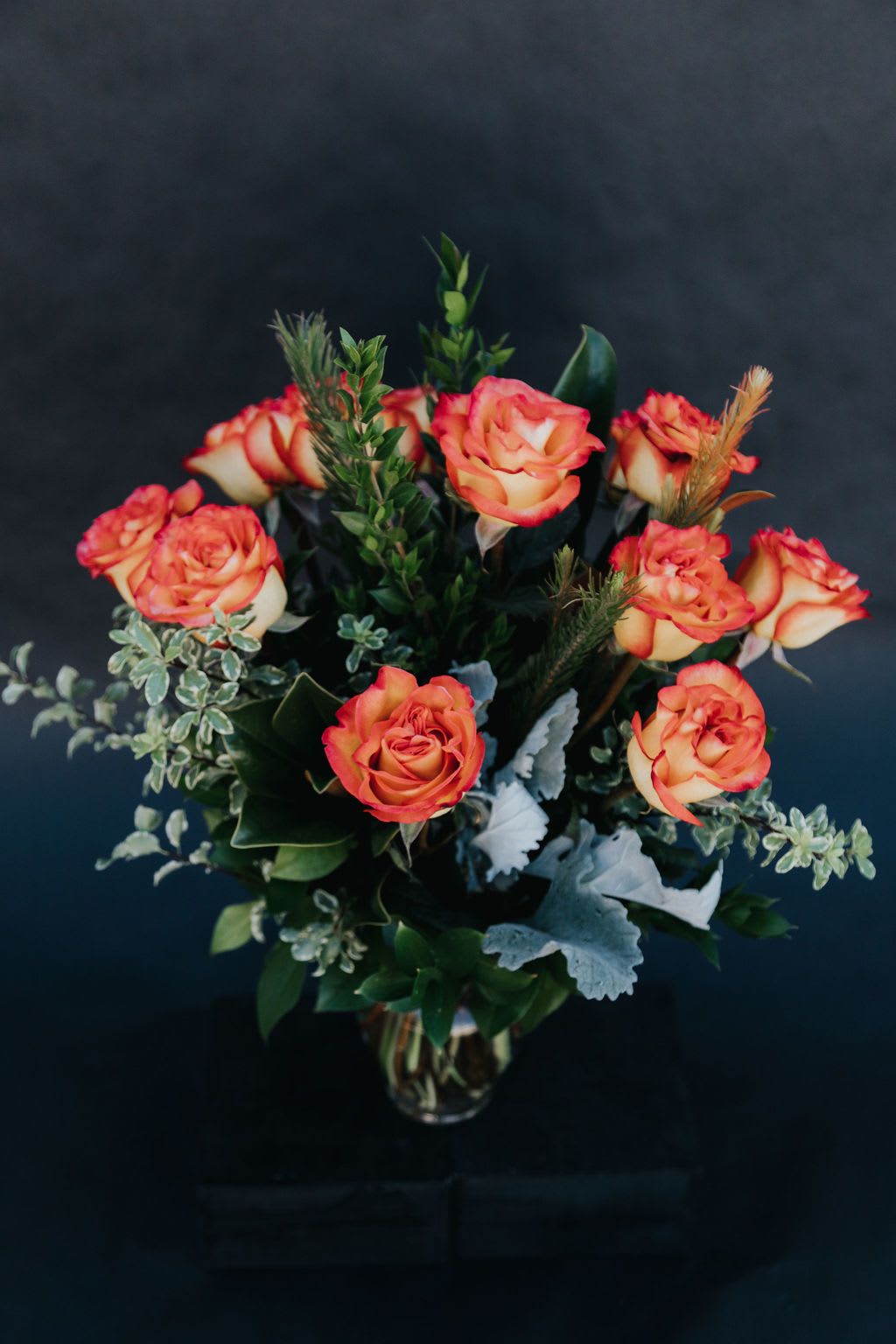 Orange and cream roses arranged in a glass vase