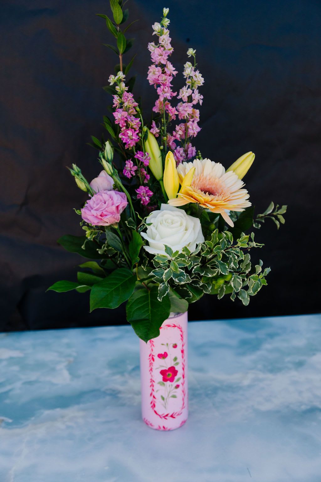 Timeless Bloom - A soft, garden-style mix of seasonal blooms in blush, ivory, and warm pastel tones, accented with fresh greenery and gentle texture. Thoughtfully arranged in a hand-painted Owala, this design pairs fresh florals with a charming keepsake she’ll enjoy long after Mother’s Day.  Order Now! Each tumbler is a one-of-a-kind, hand-painted piece sealed with a clear gloss powder coat—dishwasher safe, chip-resistant, and made to last; by artist Melanie Haggard @meligrafi. Want the tumbler without flowers? Just click the “Gift” tab at the top of the page.