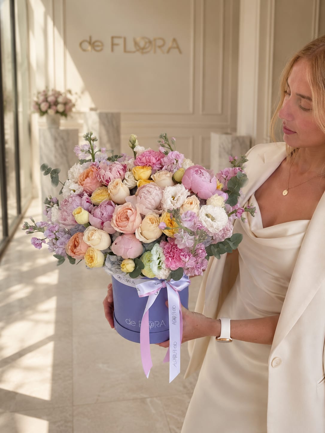 Woman holding a pastel mixed flower bouquet in a lavender hat box