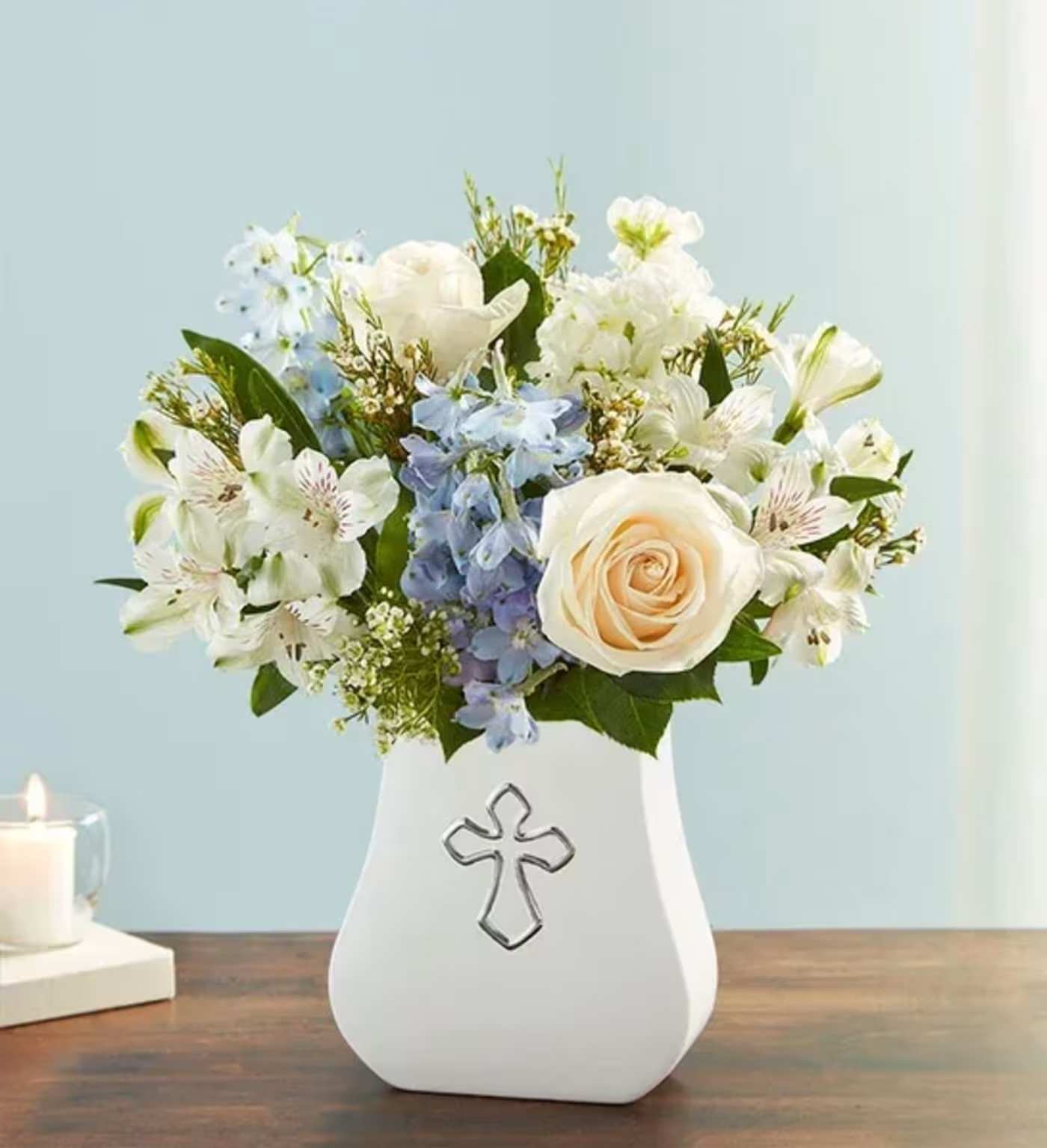 White and blue flower arrangement in a white vase with a cross emblem