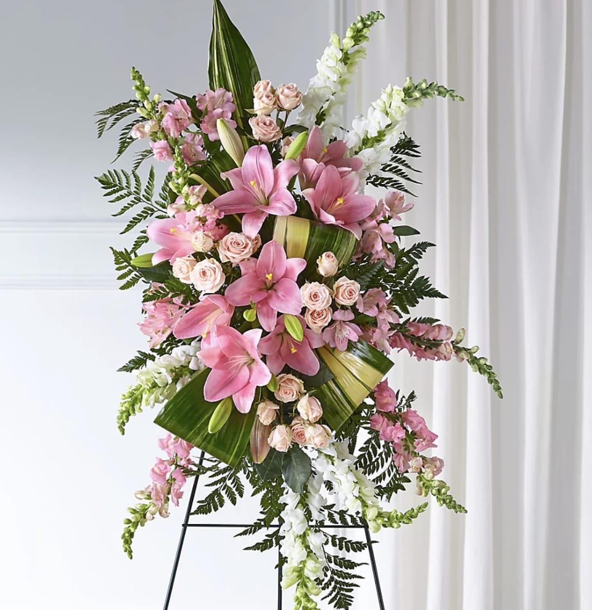 Graceful Devotion Standing Spray - Honor a cherished life with the timeless beauty of Graceful Devotion Standing Spray. Designed with fragrant pink lilies, delicate blush spray roses, graceful white snapdragons, and lush premium greenery, this standing tribute beautifully symbolizes love, admiration, and everlasting remembrance. Handcrafted by the floral designers at Bloom Luxury Box, each arrangement is thoughtfully created to bring comfort to family and friends while celebrating a life filled with treasured memories. Displayed on an easel, this elegant tribute offers a meaningful expression of sympathy and heartfelt support during life's most difficult moments.