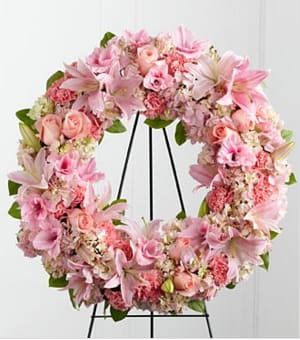 Pink Loving Remembrance (Easel Stand) - The FTD® Loving Remembrance™ Wreath is a blushing display of grace and beauty to honor the life of the deceased at their final tribute. Pink roses, Oriental lilies, gladiolus, hydrangea and carnations are brought together with lush greens to form the shape of a wreath, offering warmth and comfort with its sweetly sophisticated elegance. Displayed on a wire easel. Approximately 23-inches in diameter. Your purchase includes a complimentary personalized gift message.