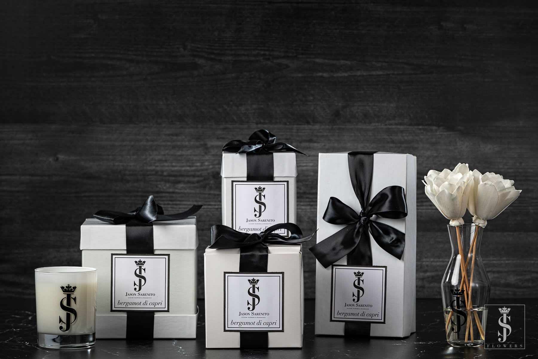Gift boxes, a candle, and white flower stems in a glass vase