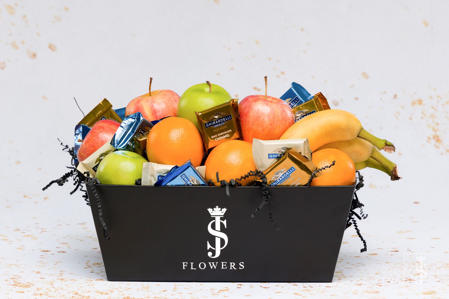 Fruit and chocolate gift box with apples, oranges, bananas, and wrapped candies