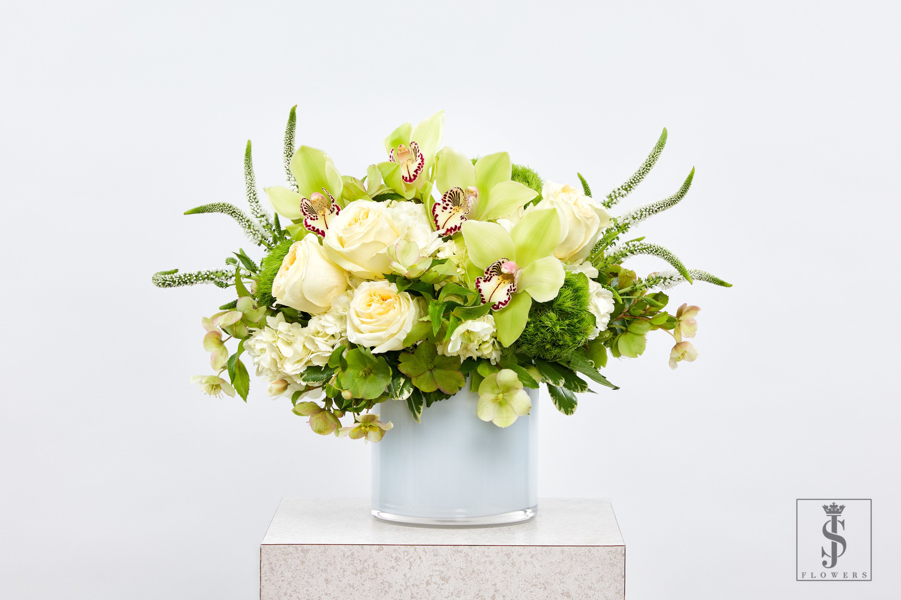 Green and white floral arrangement in a glass vase