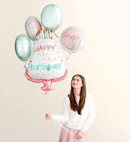 Woman holding birthday cake balloons with a "Happy Birthday" balloon
