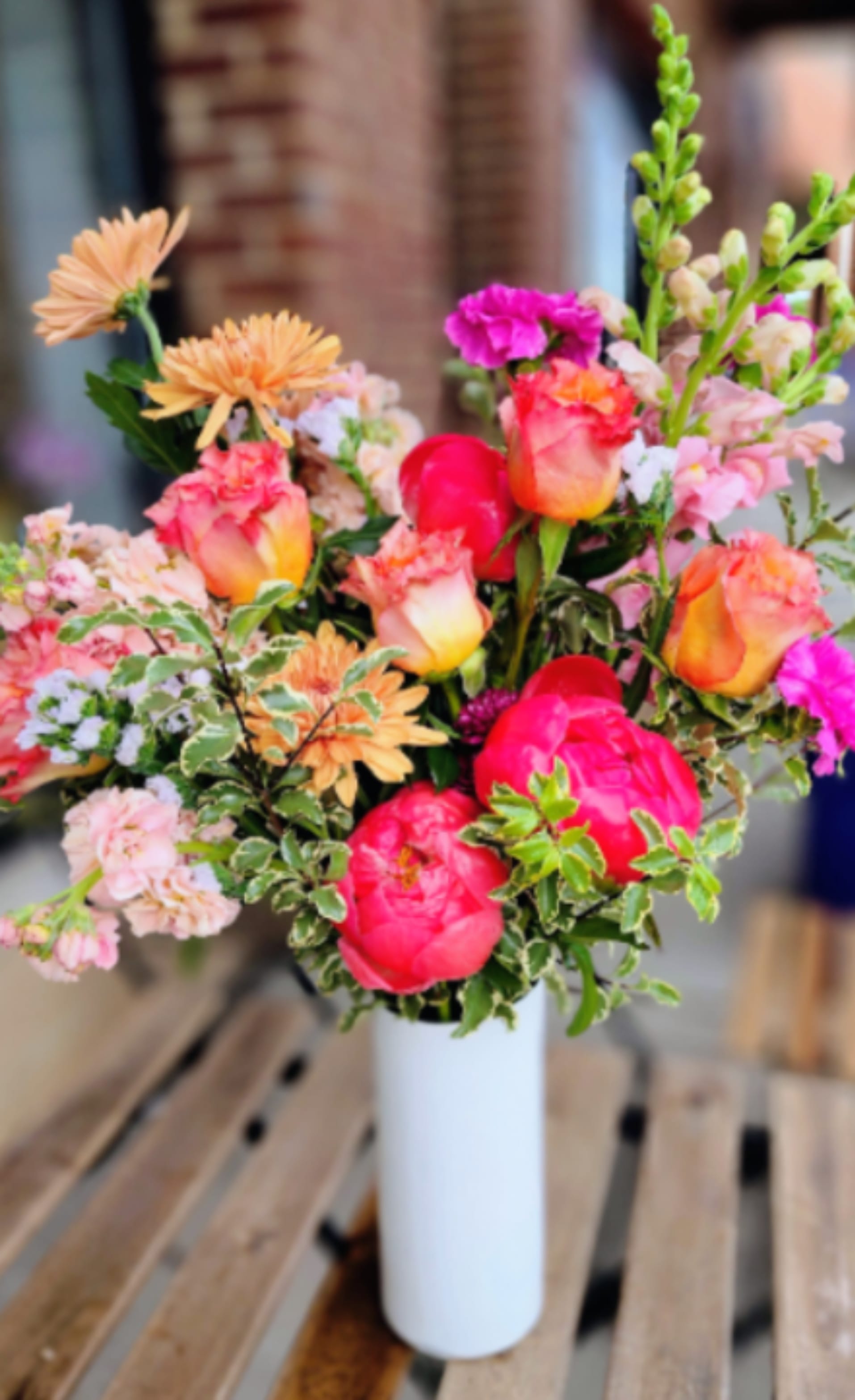 Mixed bouquet of pink and peach flowers in a white vase