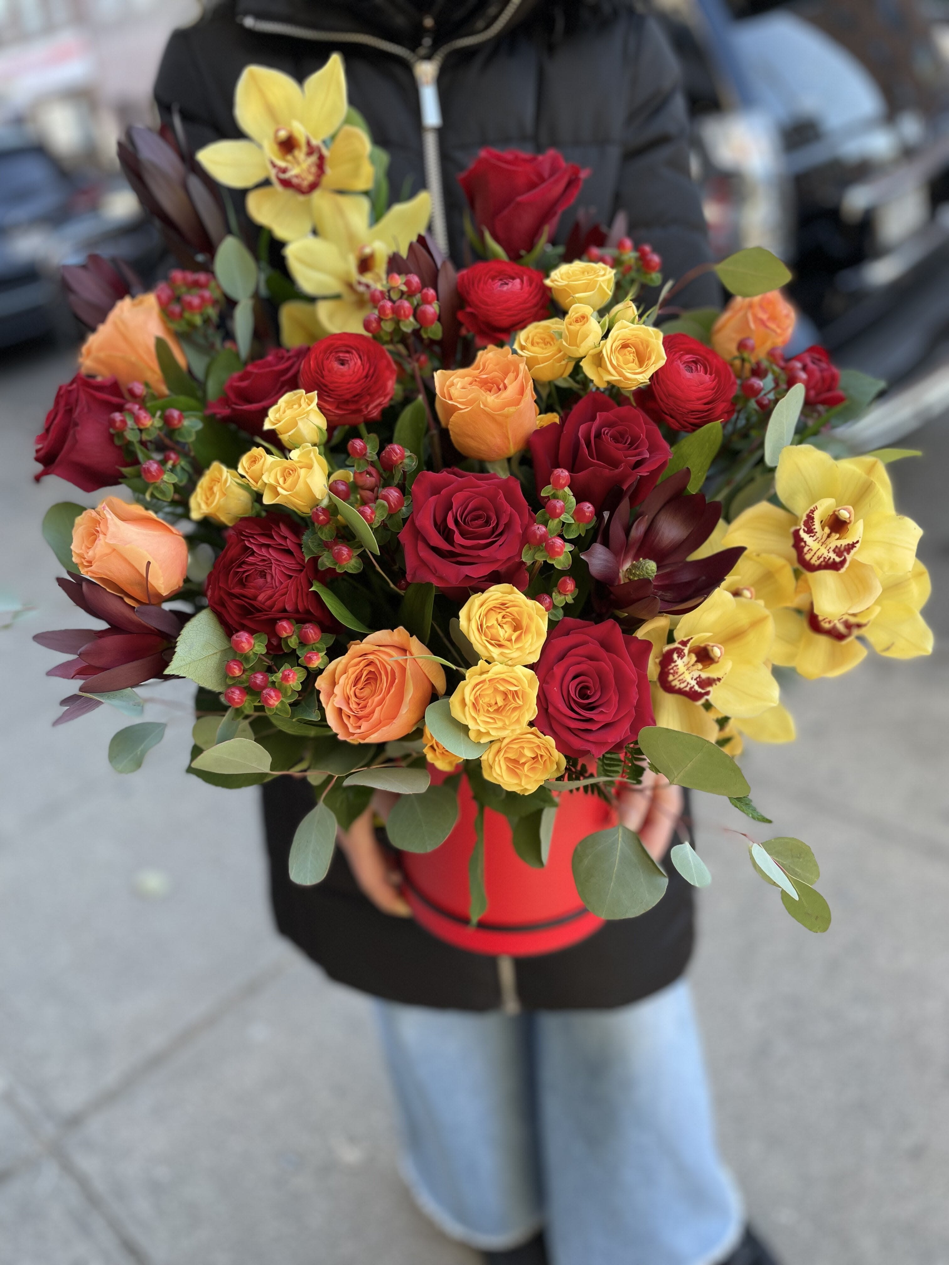 Bouquet of red, yellow, and peach roses with yellow orchids