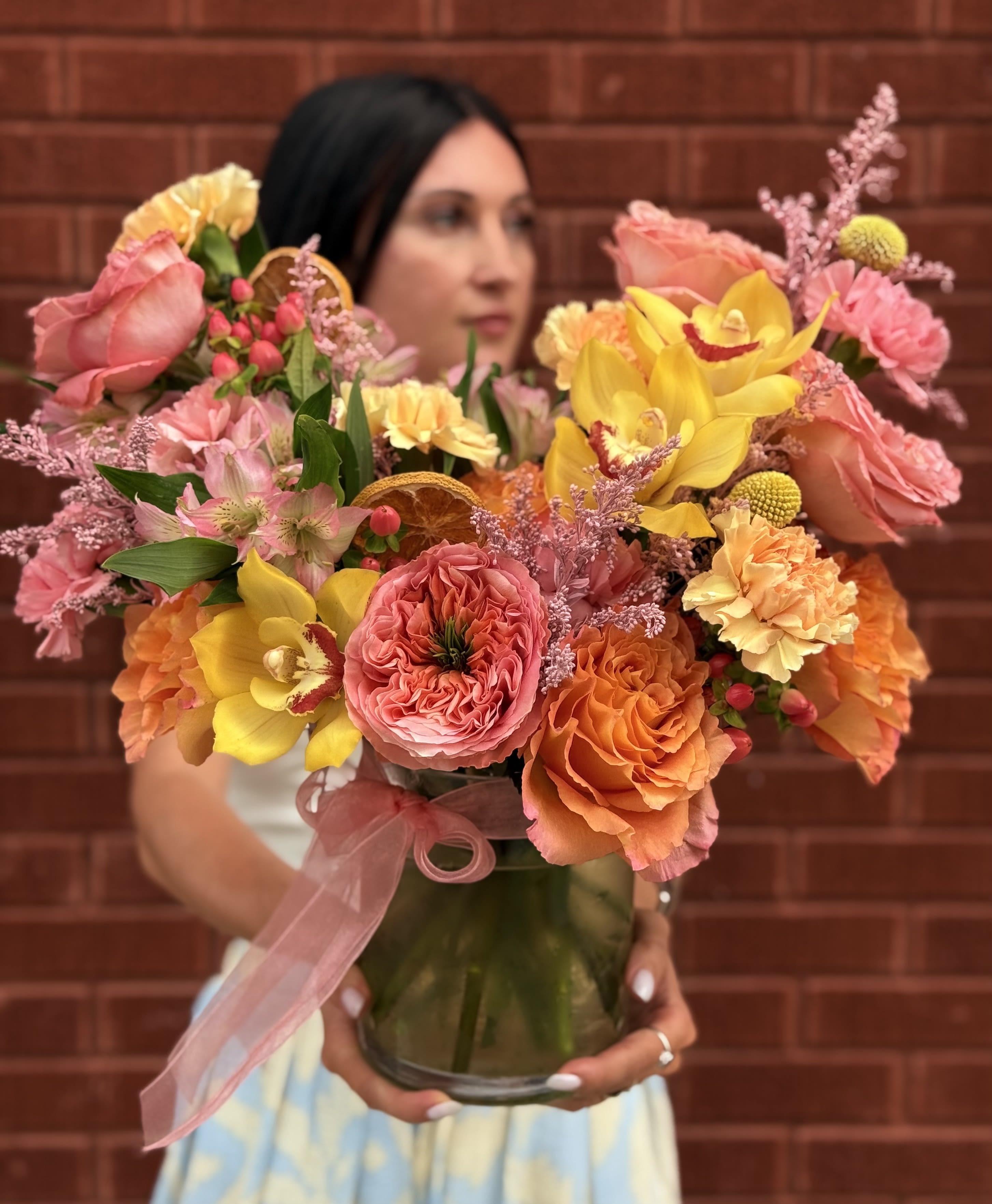 Colorful bouquet of roses, orchids, and carnations in a glass vase