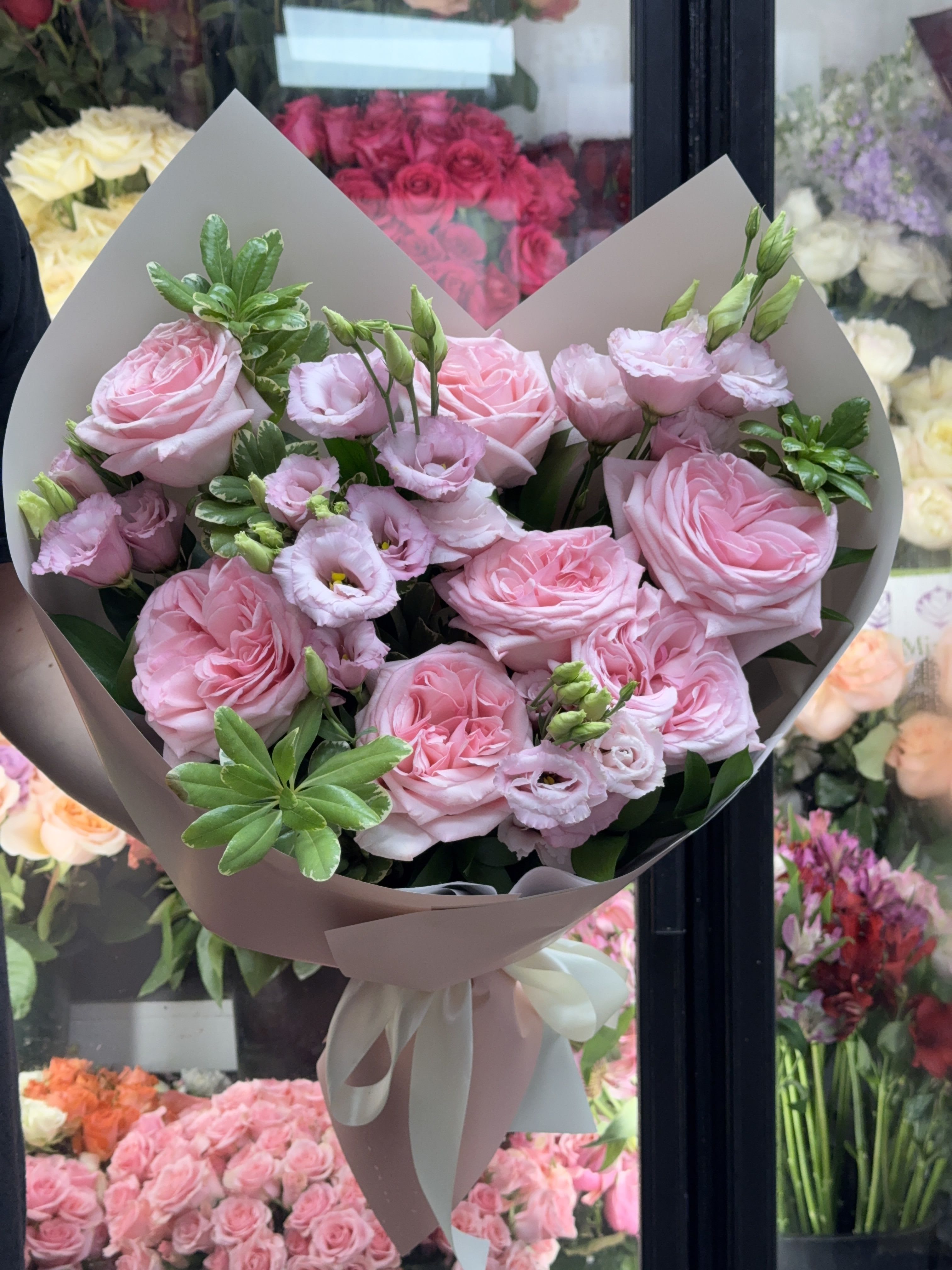 Bouquet of pink roses and pale pink lisianthus wrapped in taupe paper