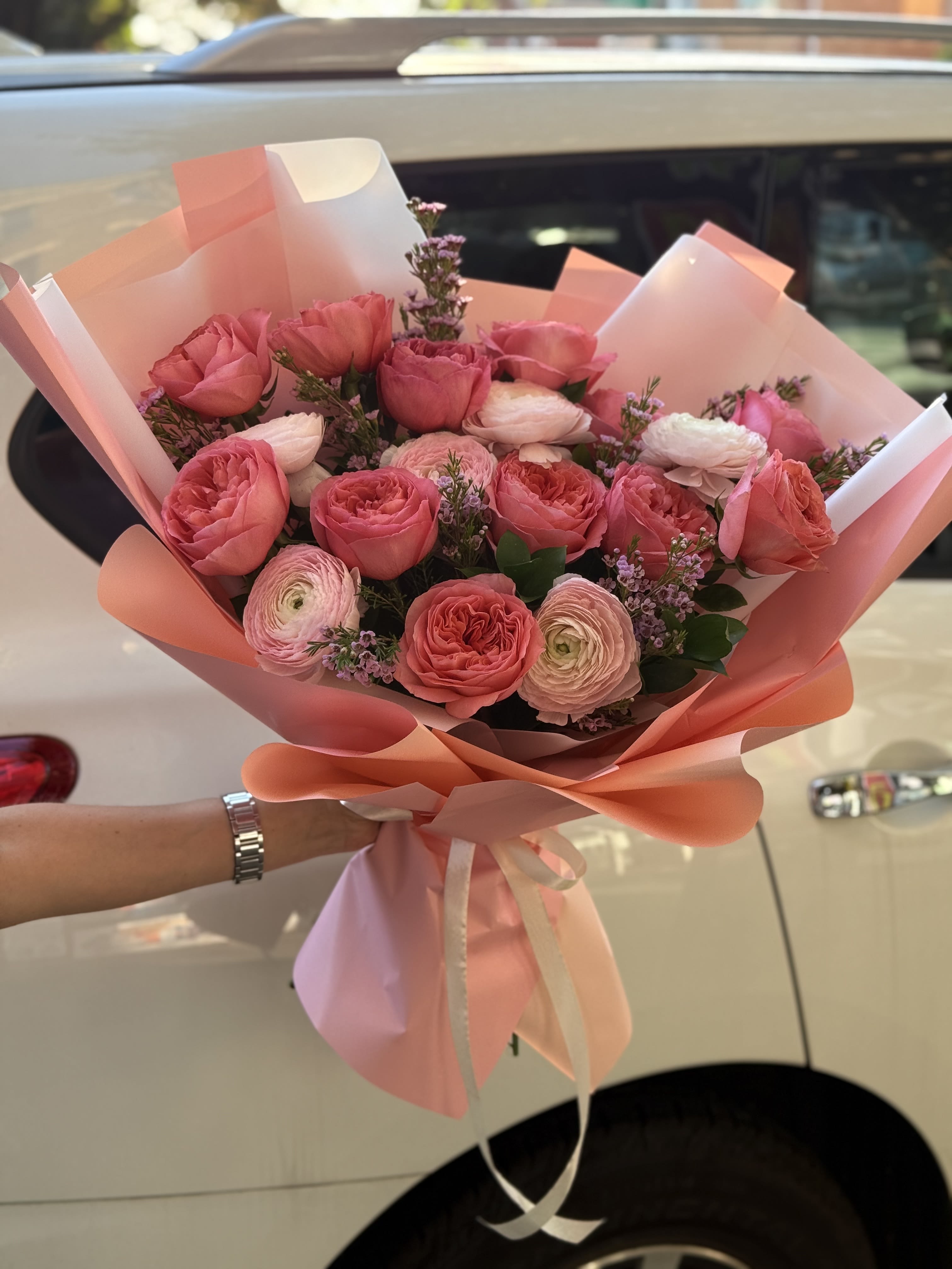 Pink rose and ranunculus bouquet wrapped in peach paper