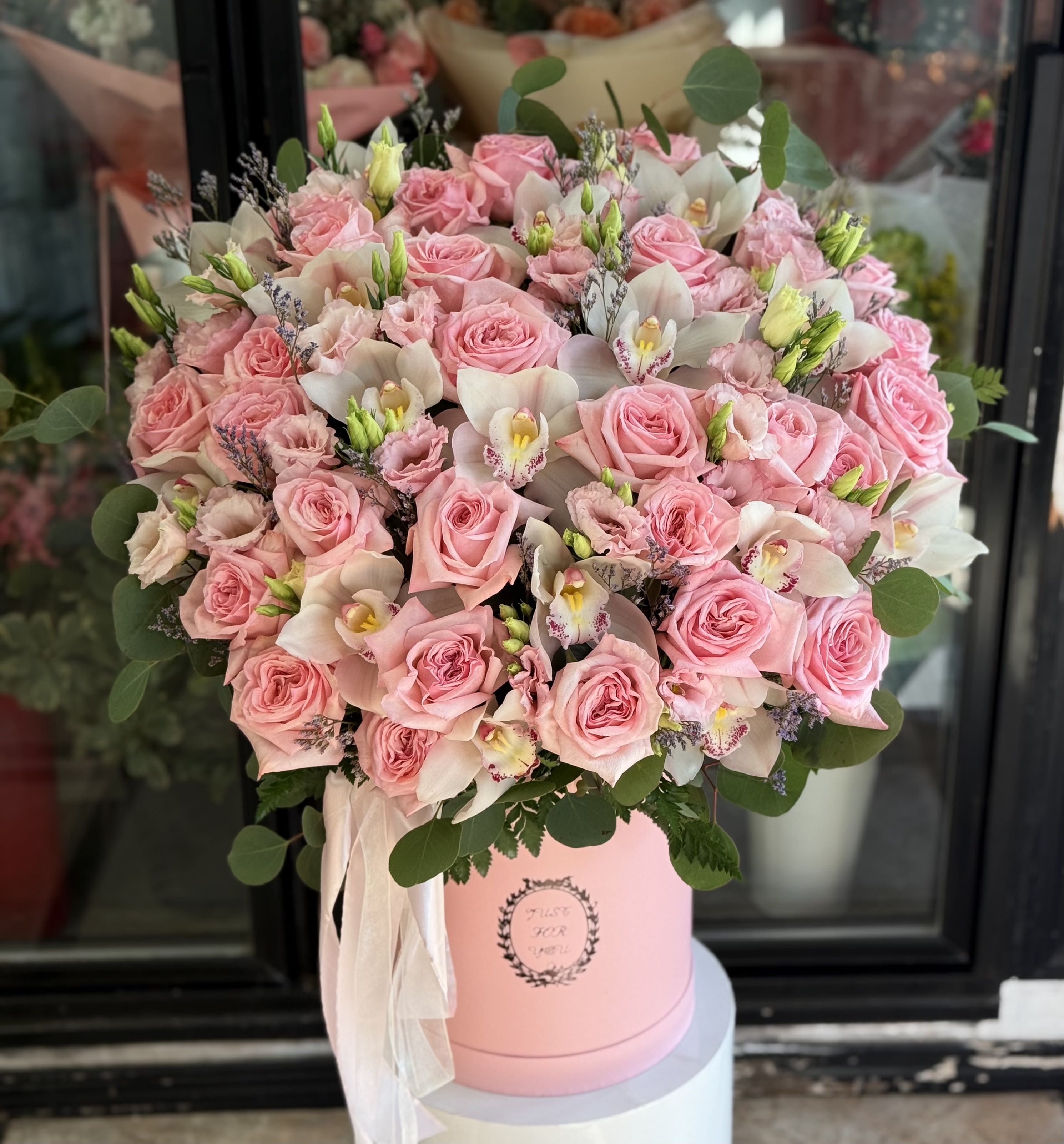 Pink roses and white orchids arranged in a pink hat box