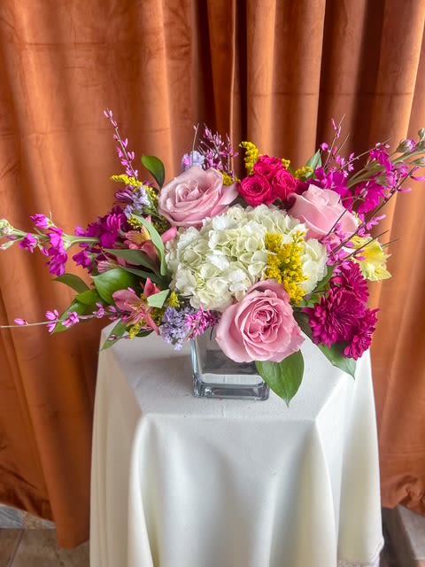 Pink and white rose arrangement in a square glass vase
