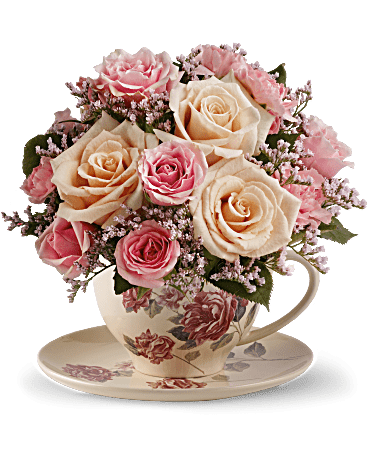 Pink and cream roses arranged in a floral teacup on a saucer
