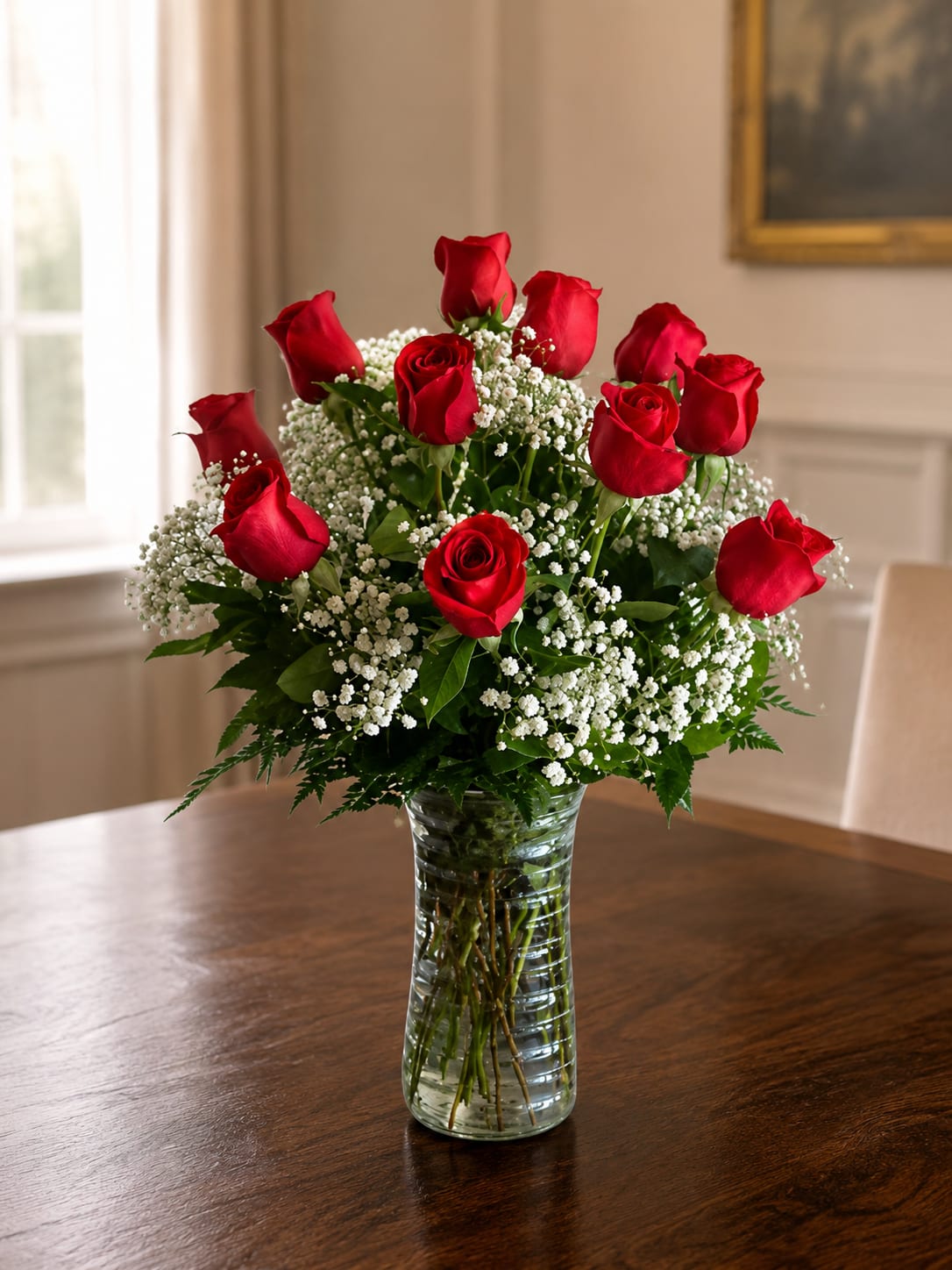 Red roses arranged in a clear glass vase with white filler flowers