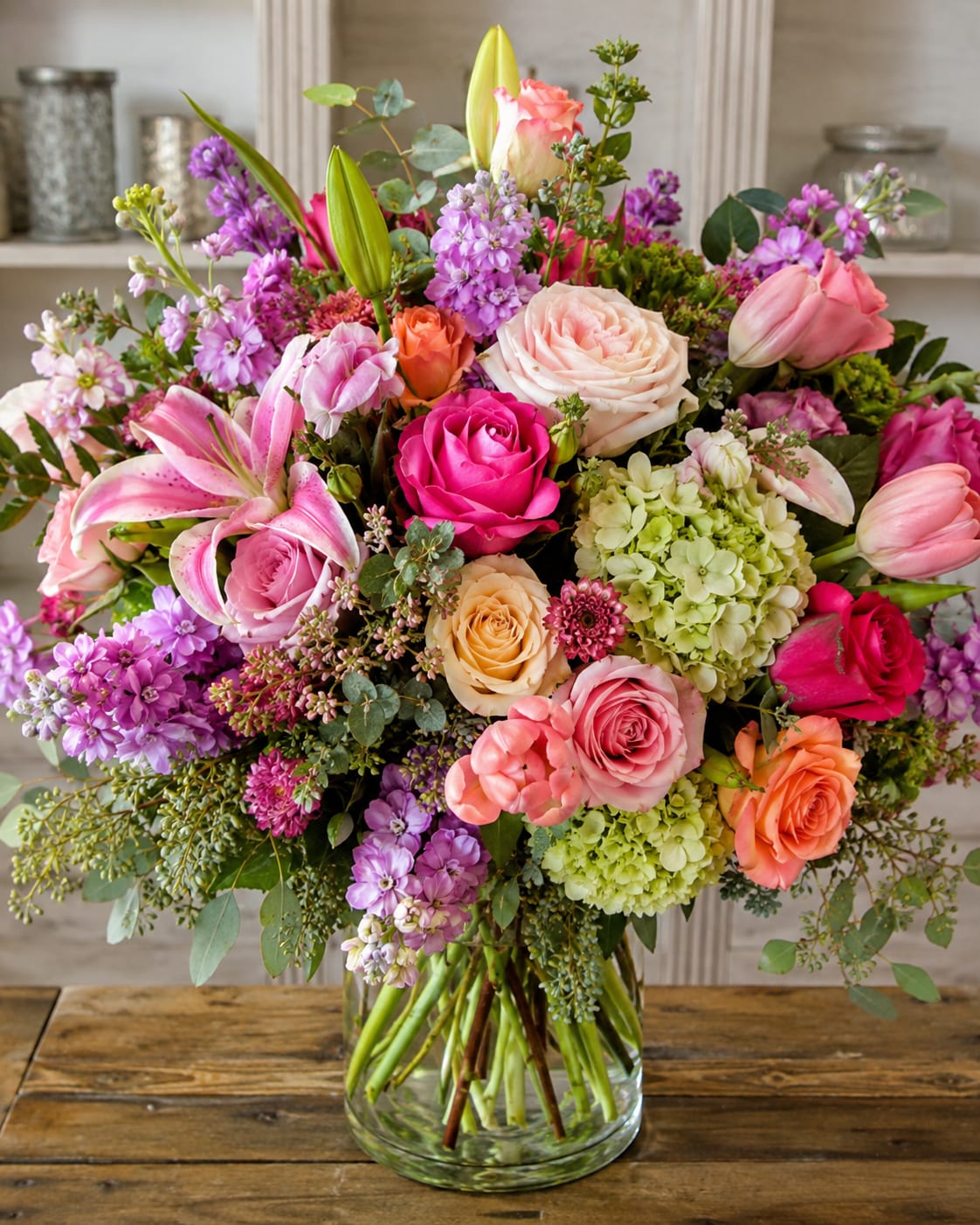 Petal Perfection's Glorious Garden for Tampa Bay - A lush, garden-style bouquet that reads like a celebration in bloom-perfect as a birthday bouquet, anniversary arrangement, or cheerful "thinking of you" gift for someone in Tampa Bay. This flower arrangement brings together pink, purple, peach, and soft white tones so the recipient feels warmly celebrated; the upright, generous composition projects both romance and joyful abundance for special occasions or everyday delight.  Built in a clear glass vase, the large mixed bouquet layers roses, lilies, hydrangeas and clusters of stock and smaller filler blooms to create a full, textured display that looks freshly gathered from a summer cutting garden. The lilies add sculptural height and soft fragrance while the hydrangeas give a voluminous, cloud-like base; roses and stock provide romantic color accents and delicate texture. The overall effect is lush and elegant without being fussy.  This is the kind of arrangement that makes the person you're sending it to feel truly seen-brightening a kitchen table, reception area, or bedside. Arrives arranged in the included clear glass vase; for best longevity, change the water every 2-3 days and trim stems slightly at an angle when refreshing-simple care keeps the bouquet looking abundant throughout the week.