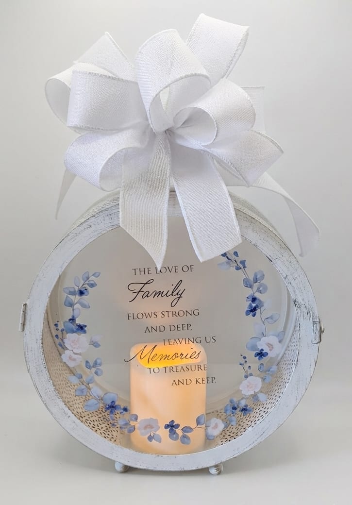 White memorial lantern with a large bow and a lit candle inside