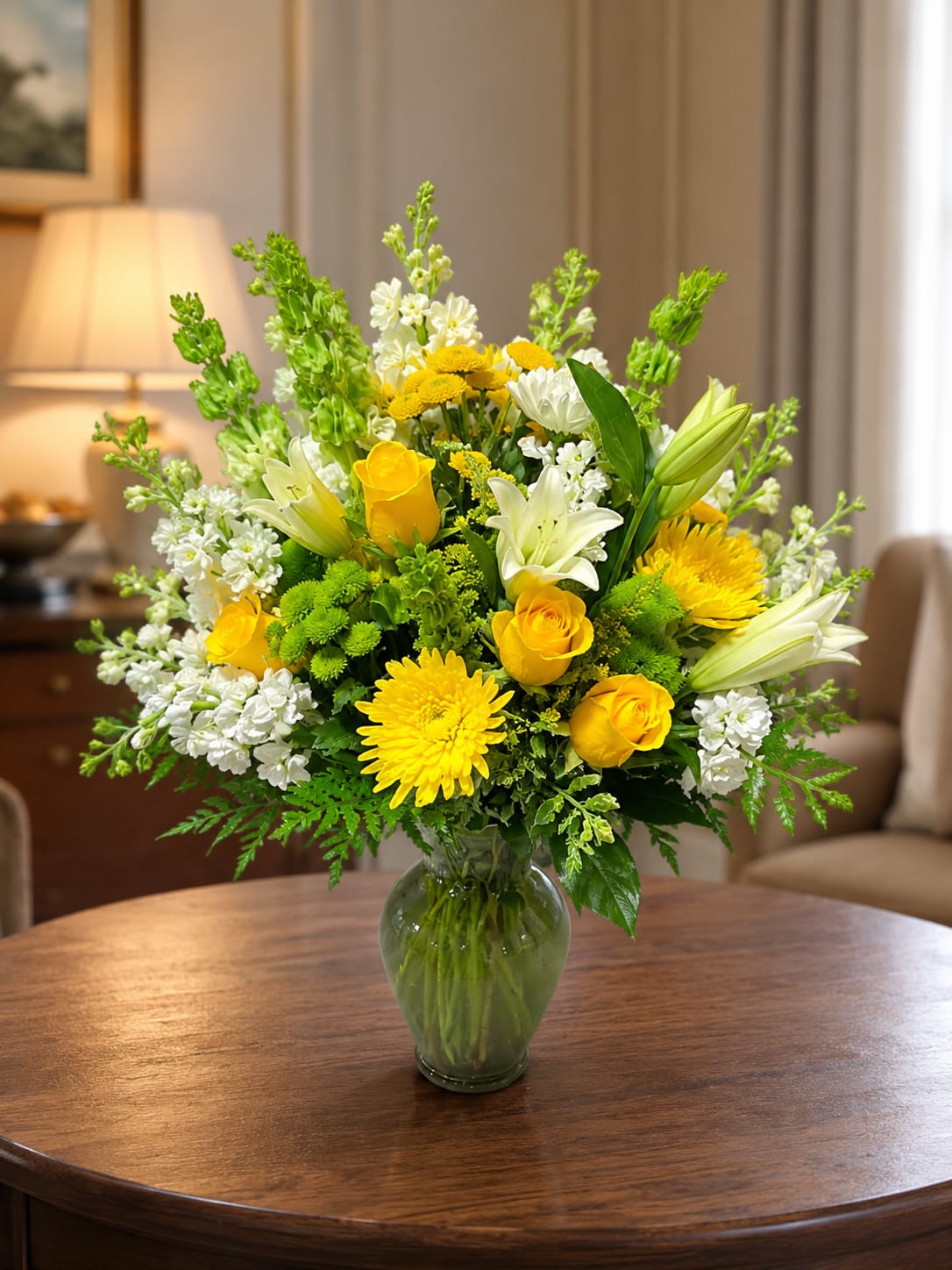 Petal Perfection’s Lemon Lime - Sunlit yellow roses and cheerful gerbera-like daisies meet crisp white lilies in a Lemon Lime flower arrangement designed to brighten any room - perfect as a birthday bouquet, Mother's Day surprise, get well gift, or an uplifting everyday gesture. The tall, airy silhouette makes this flower arrangement especially fitting for spring and Easter décor while remaining joyful and versatile for summer, anniversaries, new baby celebrations, or simply saying "I'm thinking of you."  This composition pairs yellow, green, and white blooms with vertical Bells of Ireland to add elegant height and structure, arranged in a green-tinted glass vase for a fresh, modern look. The mix of textured petals and upright greens creates visual movement and a light, hopeful feel; the lilies add fragrance while the roses and daisy-like flowers deliver long-lasting color. Sized to stand out on a mantle or brighten a bedside table, Lemon Lime is an uplifting choice for housewarmings, graduations, sympathy, or holiday gatherings - and it's easy to care for with regular water changes and fresh cuts to the stems for longer enjoyment.