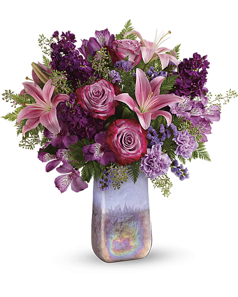 Pink lilies and roses arranged in a tall iridescent vase
